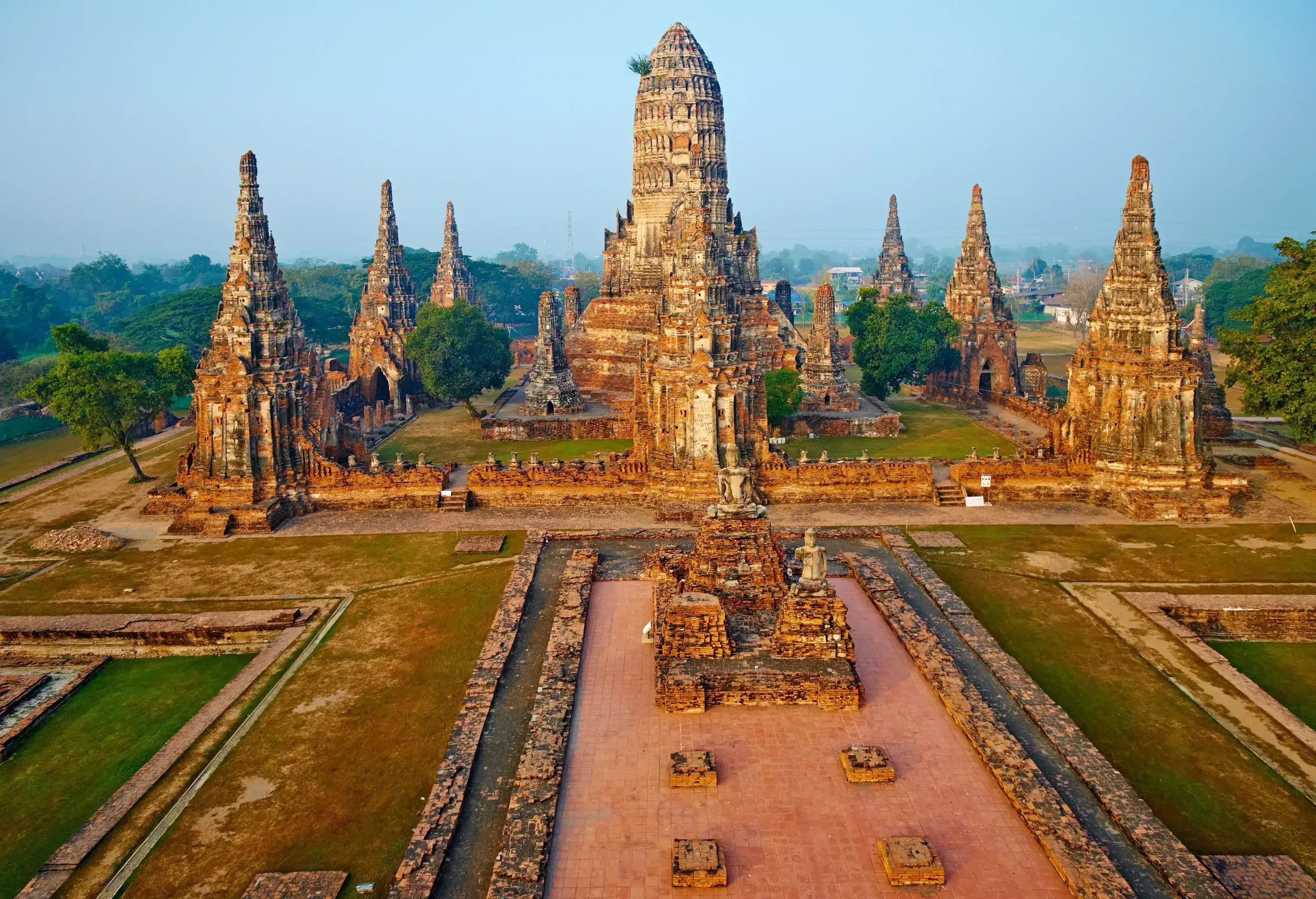 A magnificent Buddhist temple complex, Wat Chai Wattanaram, featuring a central prang surrounded by smaller prangs and chedis, adorned with intricate carvings and sculptures, evoking a sense of grandeur and spiritual serenity.