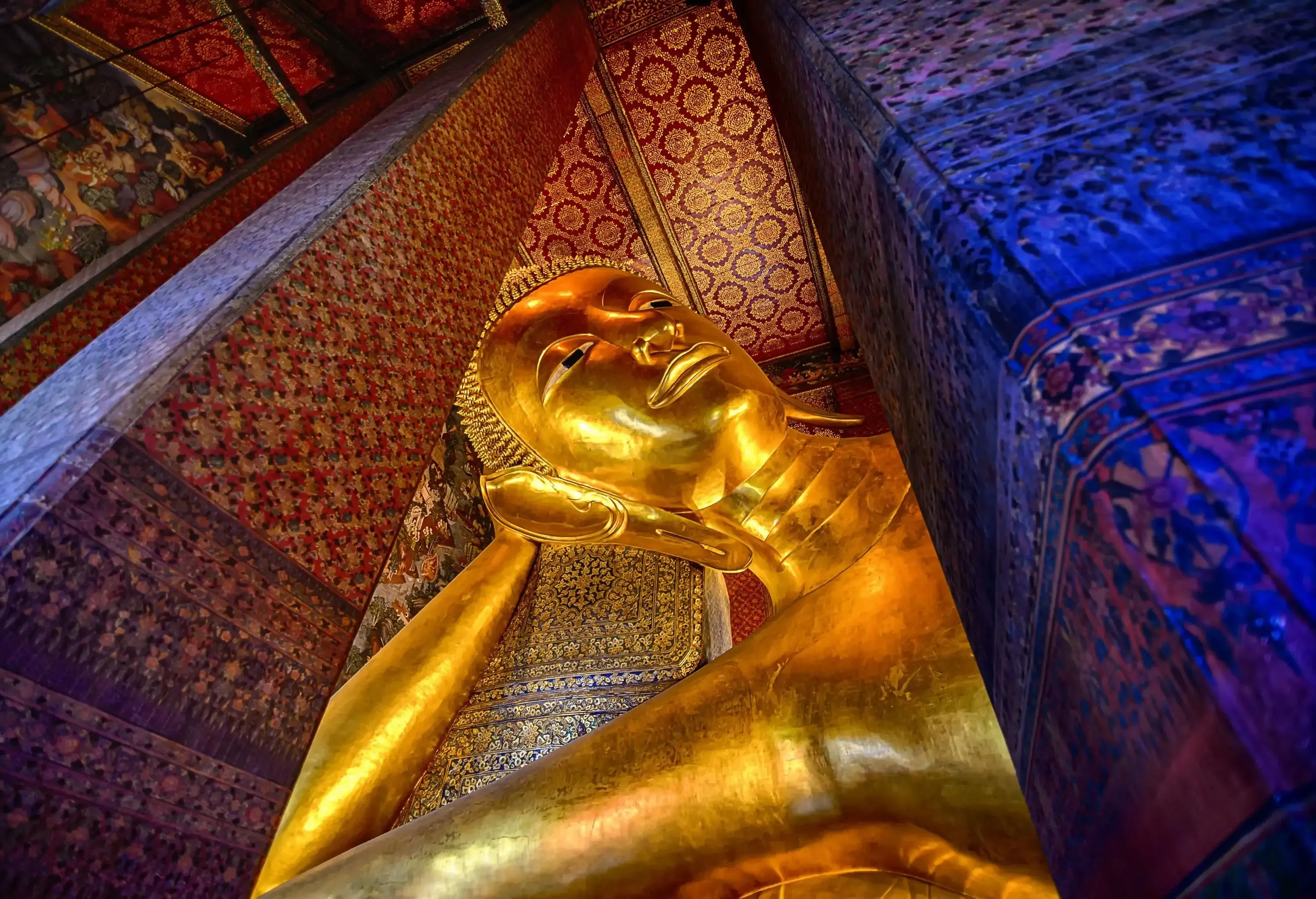 The enormous golden statue known as the Reclining Buddha depicts the Buddha lying on its side with its right hand resting on its head.