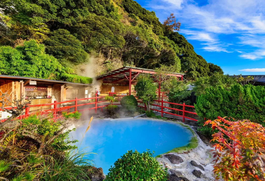 A pond of steaming blue water surrounded by trees.