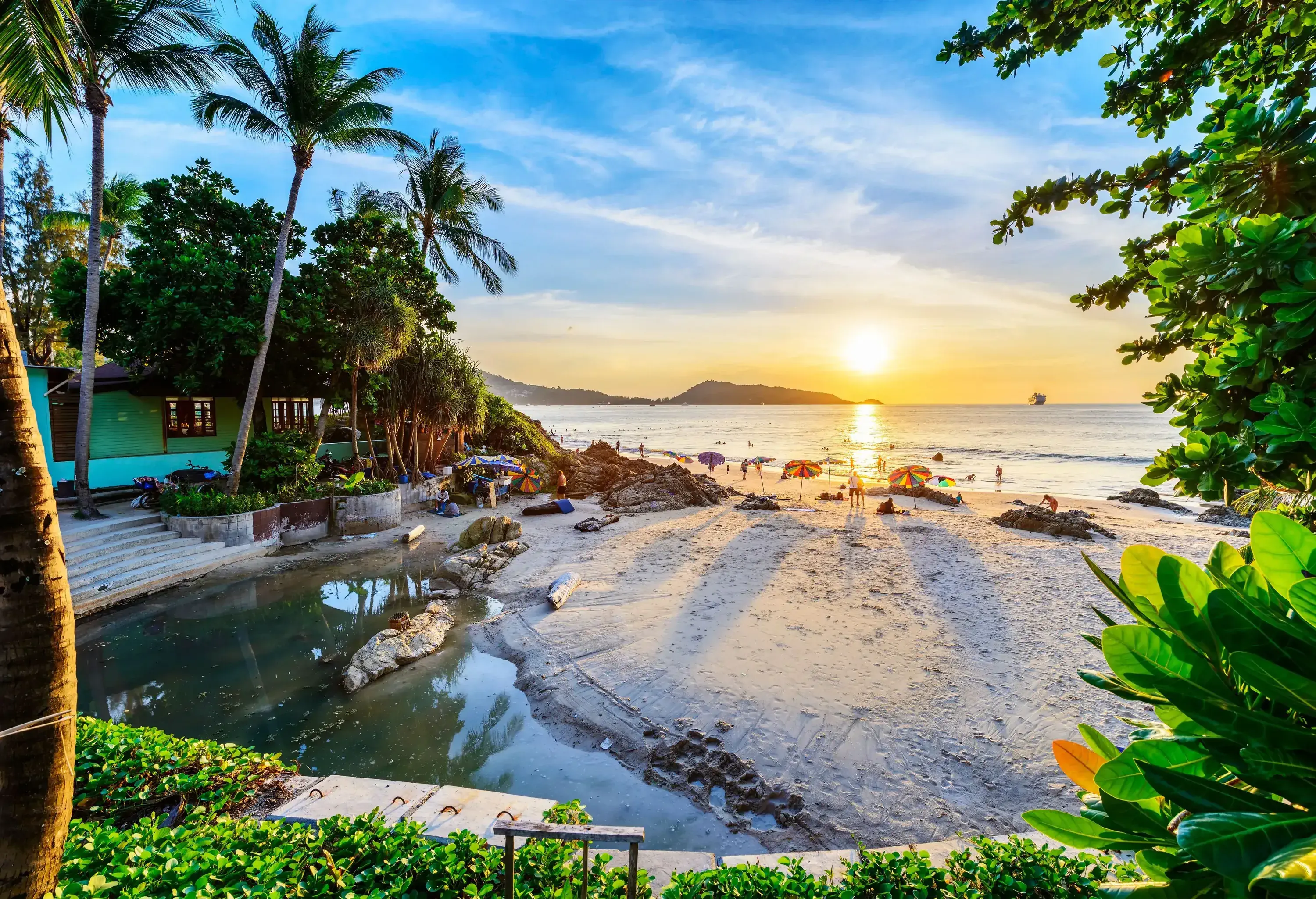 A pond near the beach with colourful umbrellas and tourists under the scenic sun.