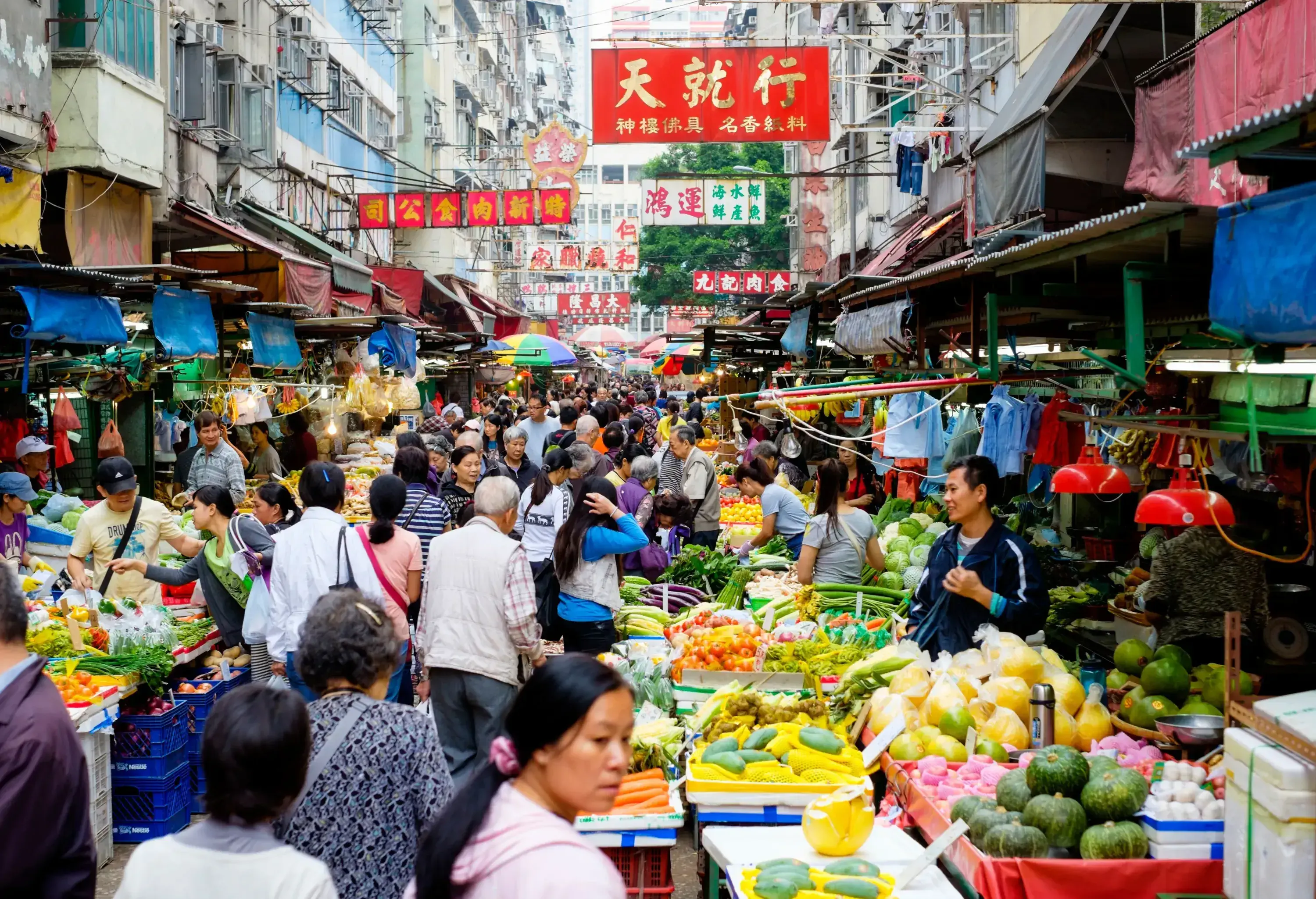 A bustling street produce market, abutted by a vibrant assortment of buildings.