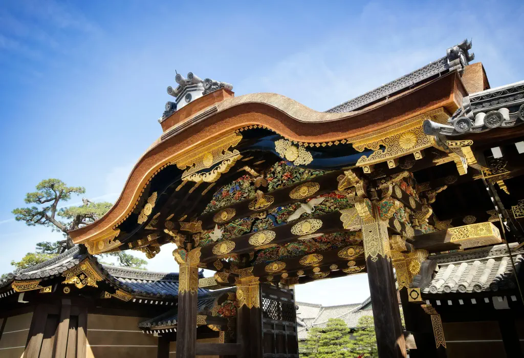 A castle gate with intricate golden carvings of cranes, pines, bamboos, and flower blossoms.