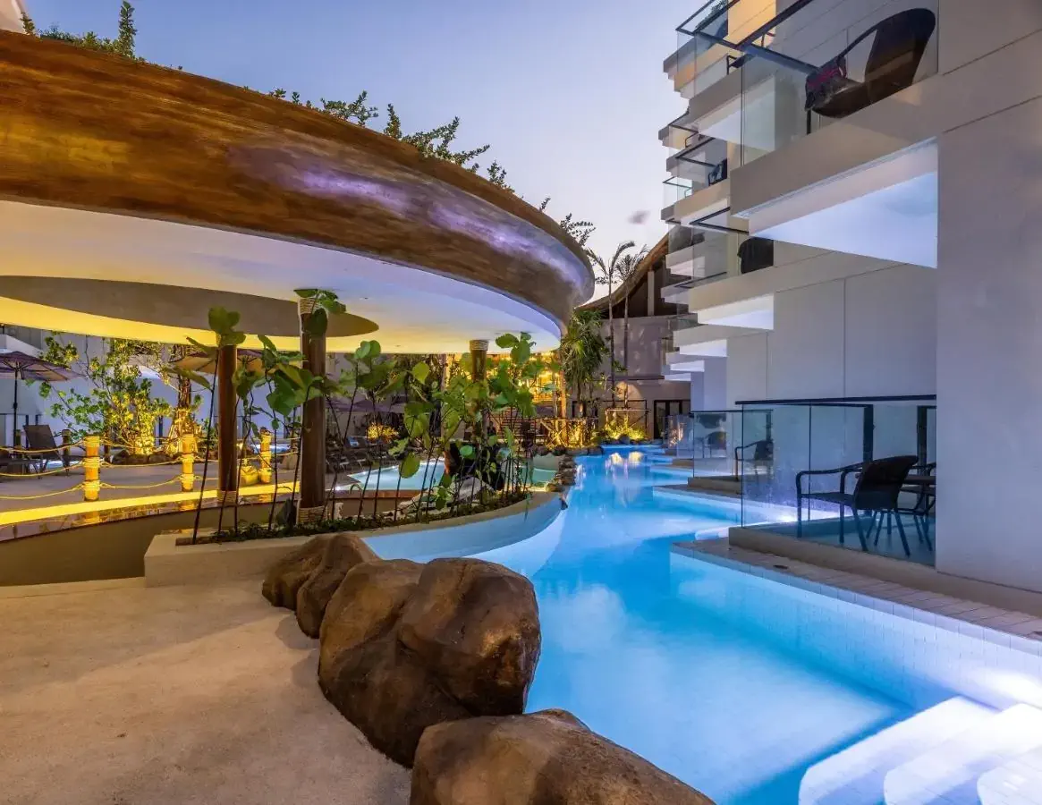 Modern elegant hotel resort with exterior pool and building around it at dusk