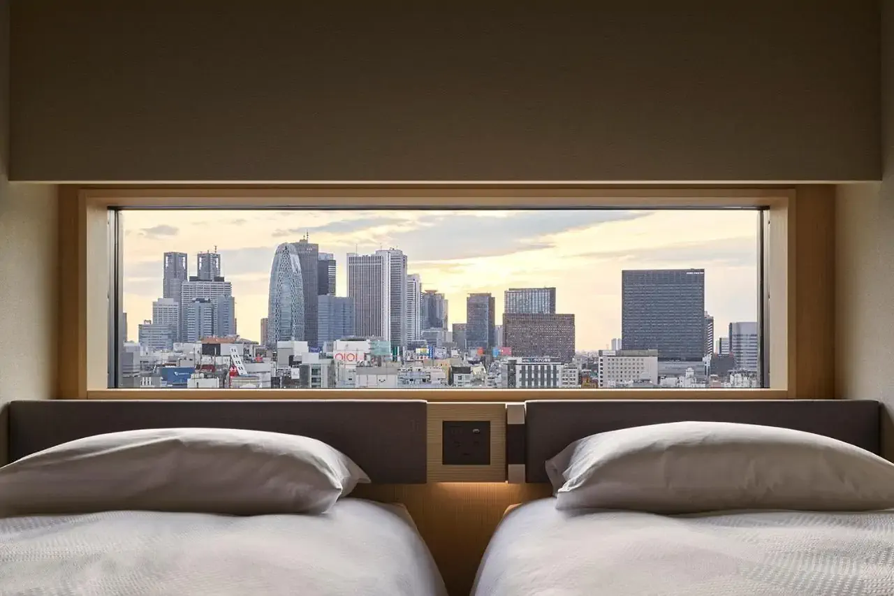 Twin beds by a window overlooking a city with high rise buildings
