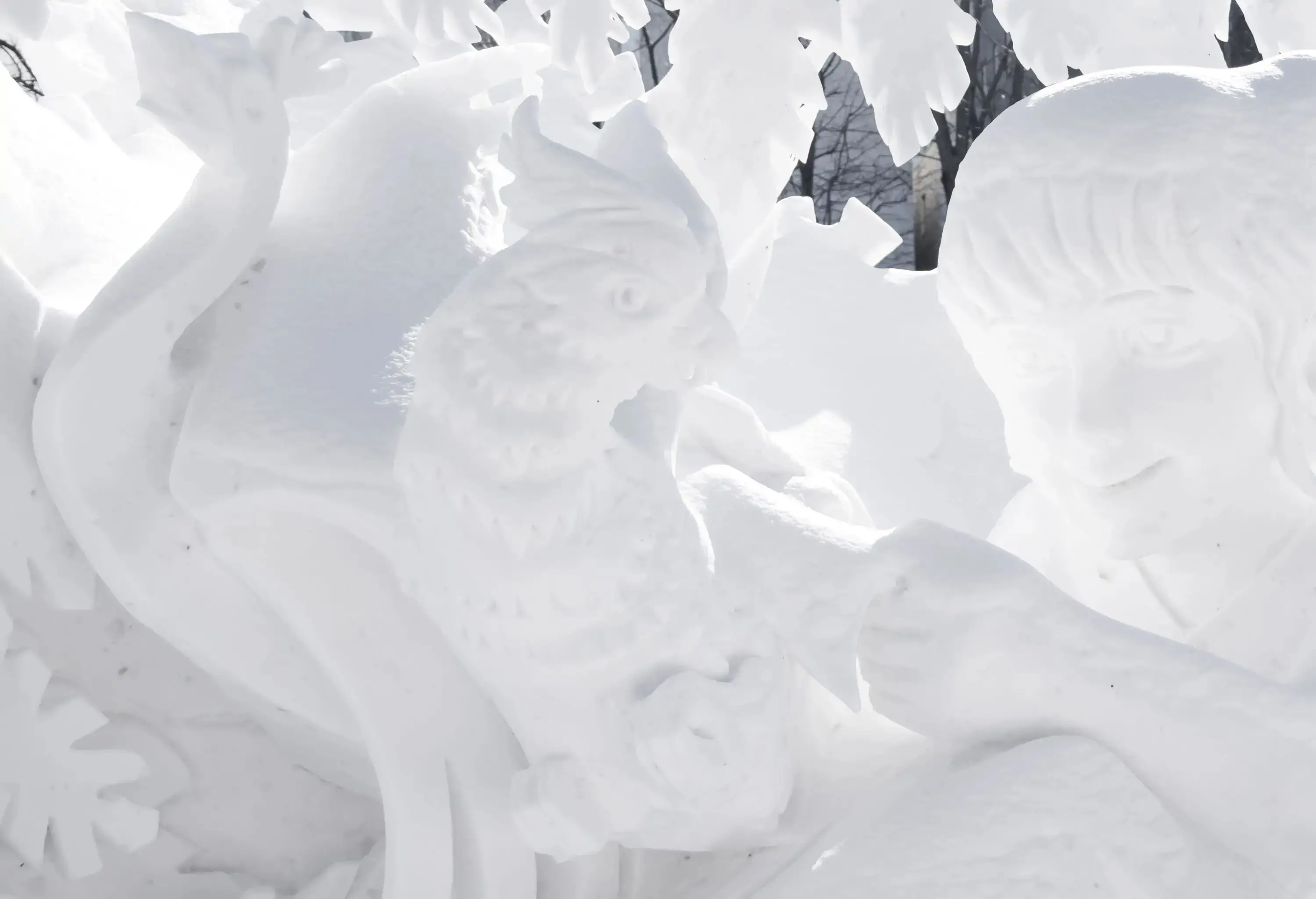 Intricate snow carvings of a person holding a rooster.