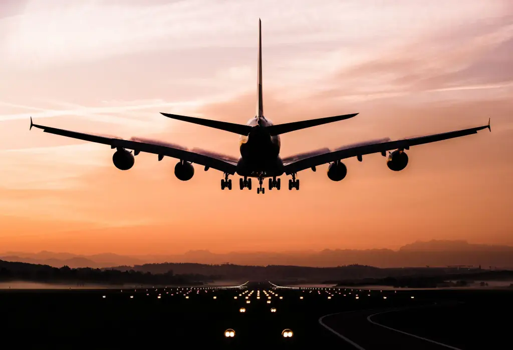 An airplane preparing to land on a runway with its guard lights on.