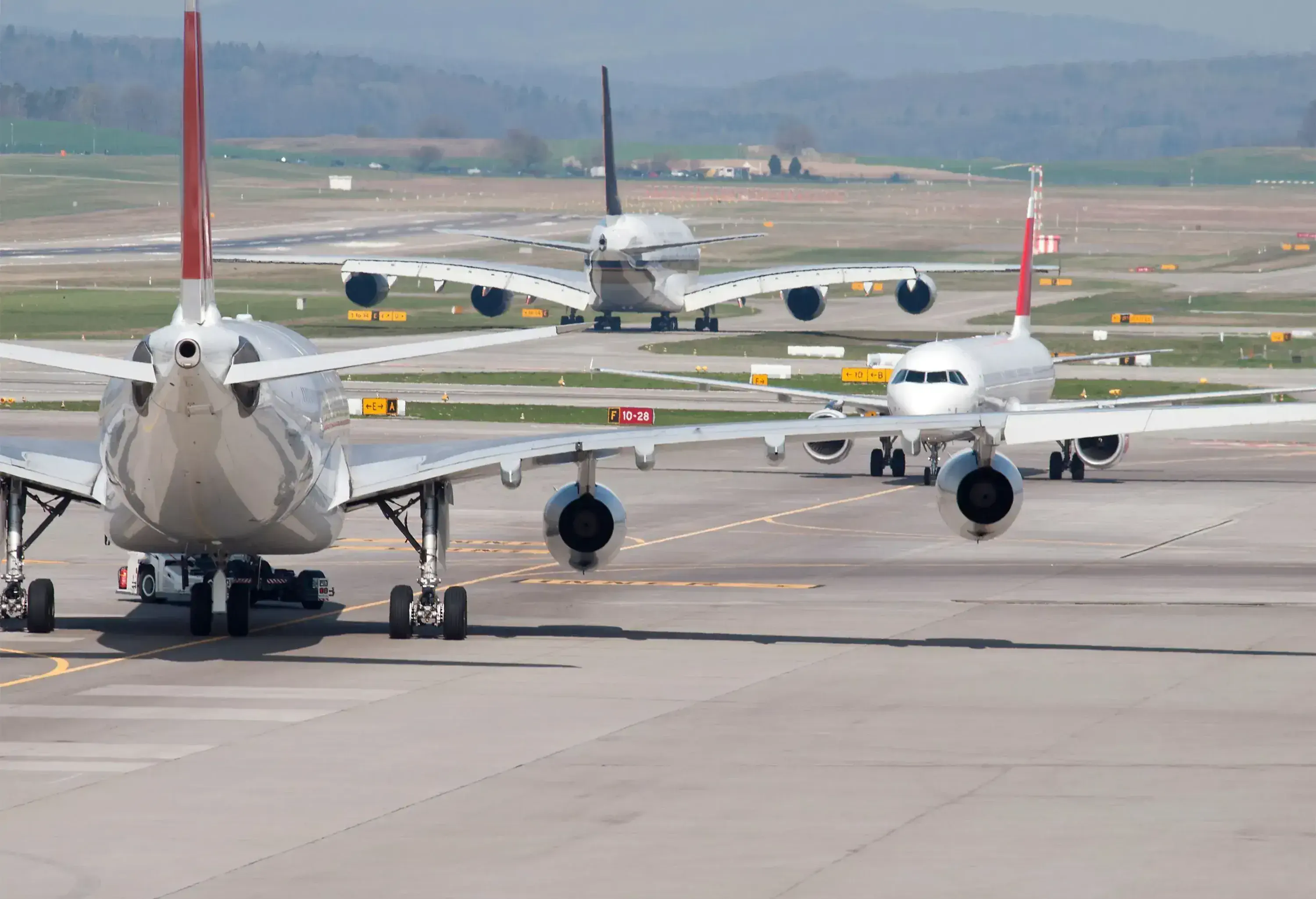 Three passenger aircrafts in heavy traffic on the taxiway of Zurich international airport. Aircraft types on picture include Airbus A380 (middle). Two moving away, one approaching. Looks like the aircrafts are deadlocked in a taxiway traffic jam.
