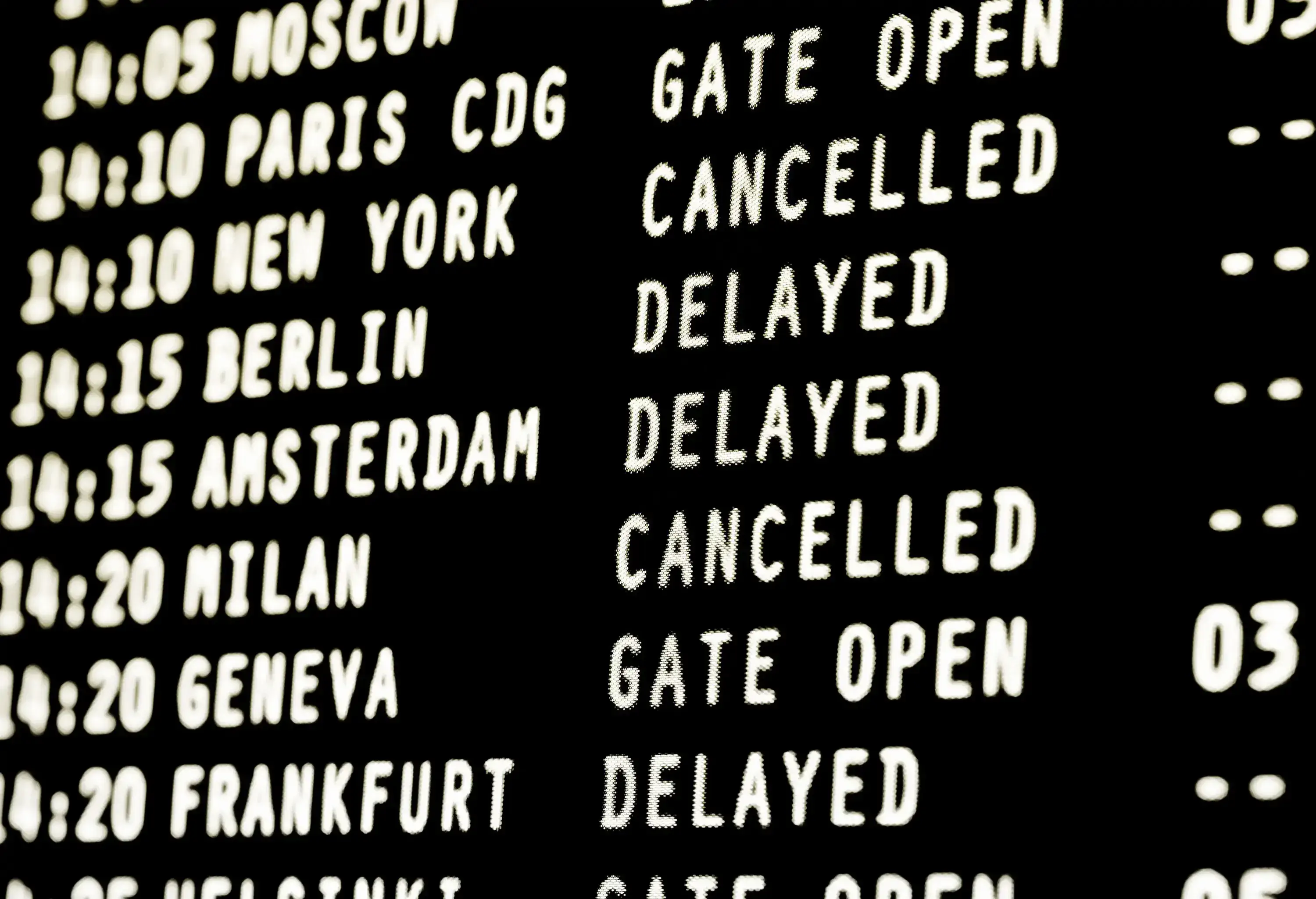 A close-up of an airport departure board showing various flight destinations and status.