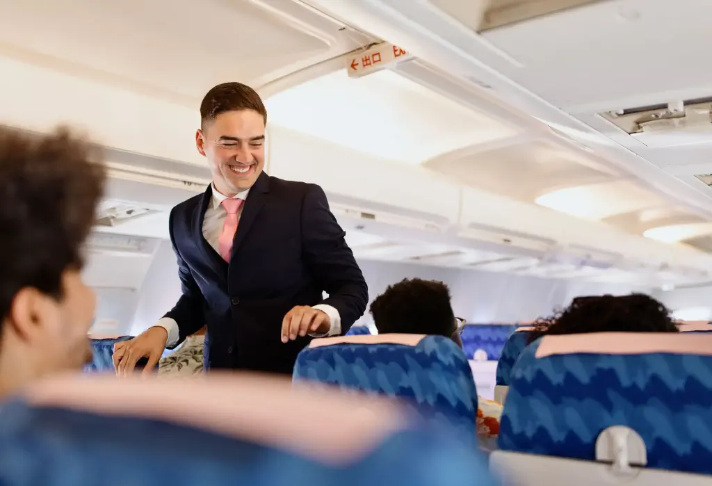 Male flight attendant checking on the passengers before take off
