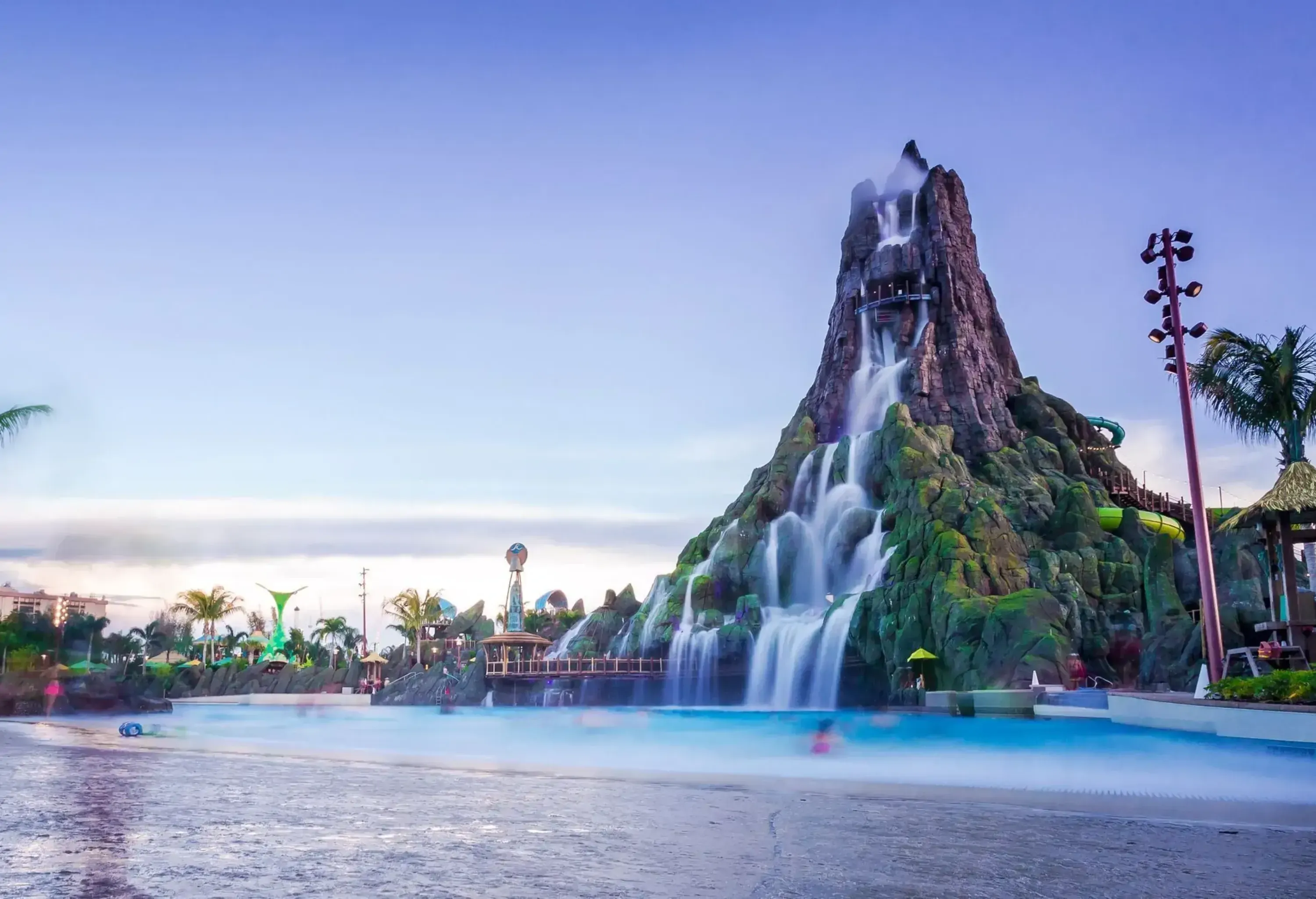 A water theme park with a waterfall cascading the tall artificial volcano.