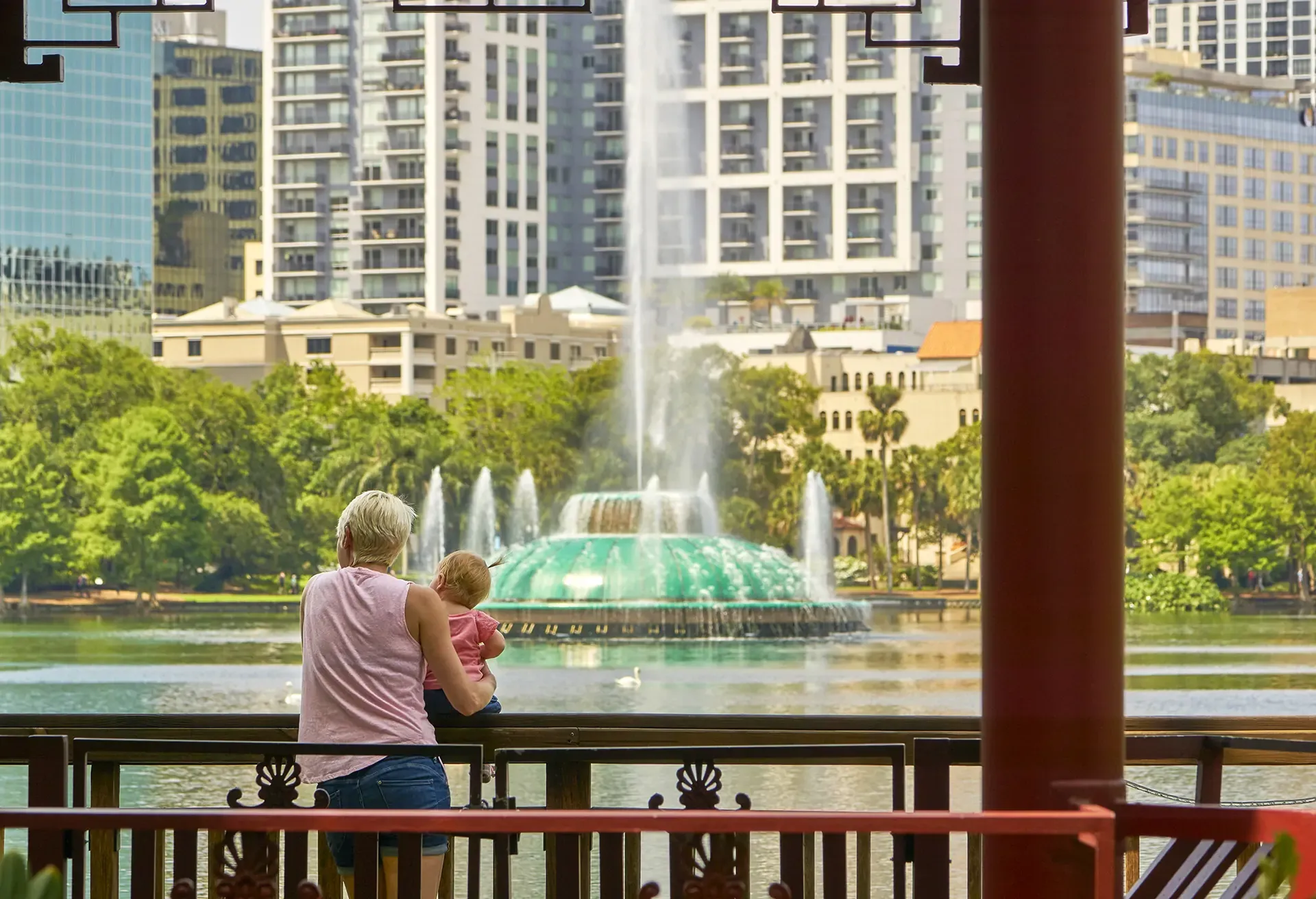 Mother and baby daughter looking over an urban lake in a city-1220571846