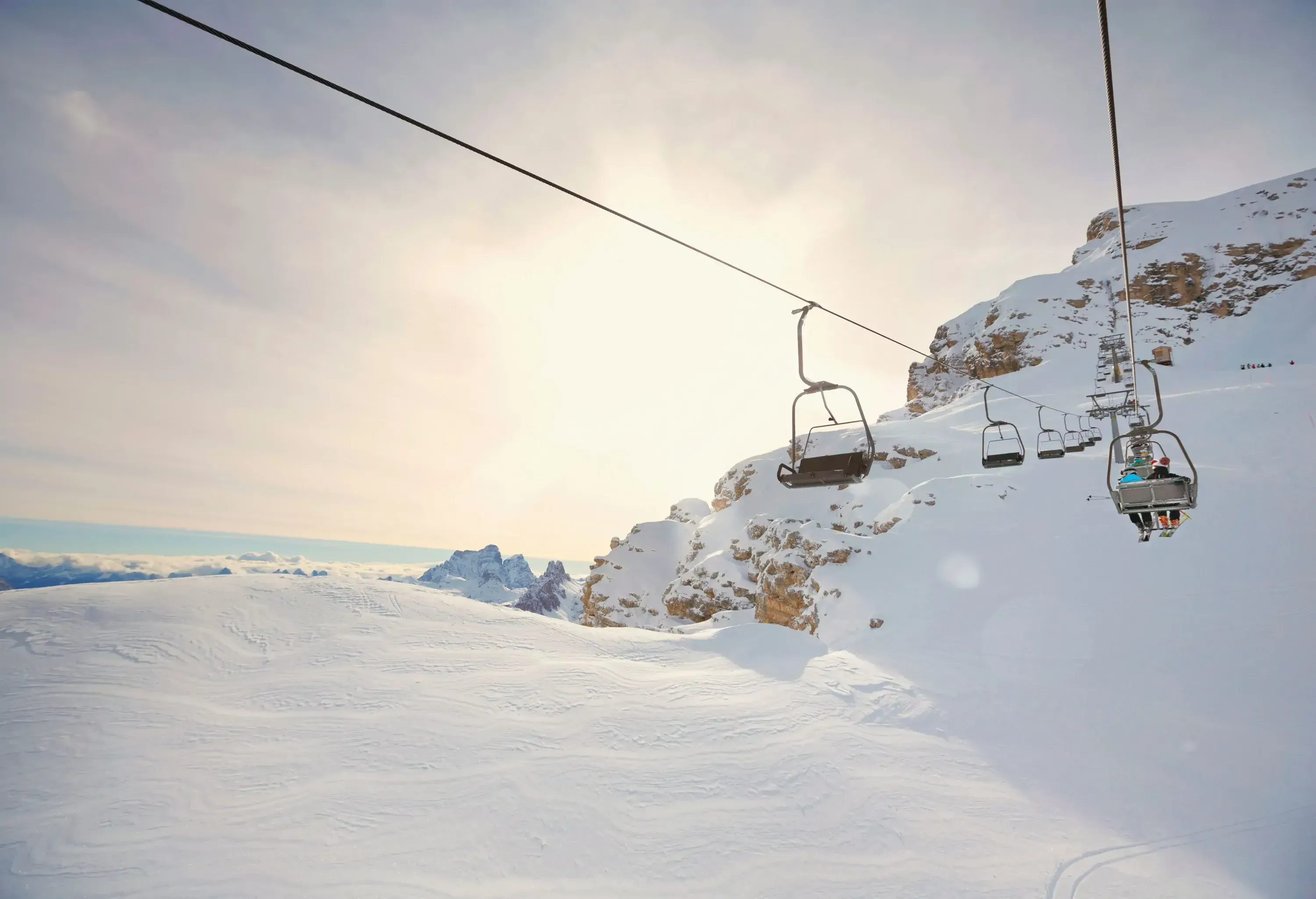 People on the ski chairlift above deep powder snowland.