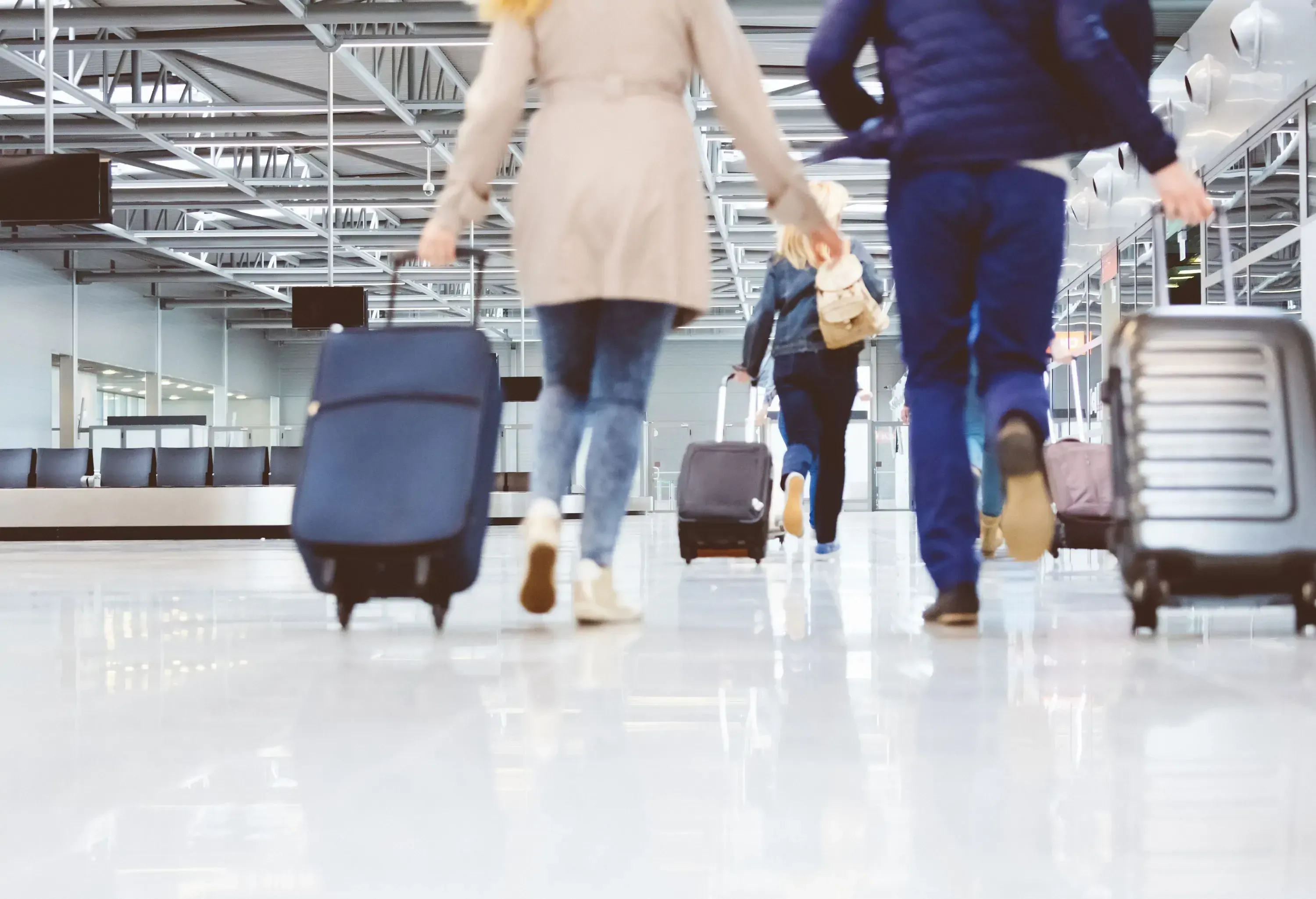 Rear view of passengers pulling their suitcases leaving the baggage claim area.