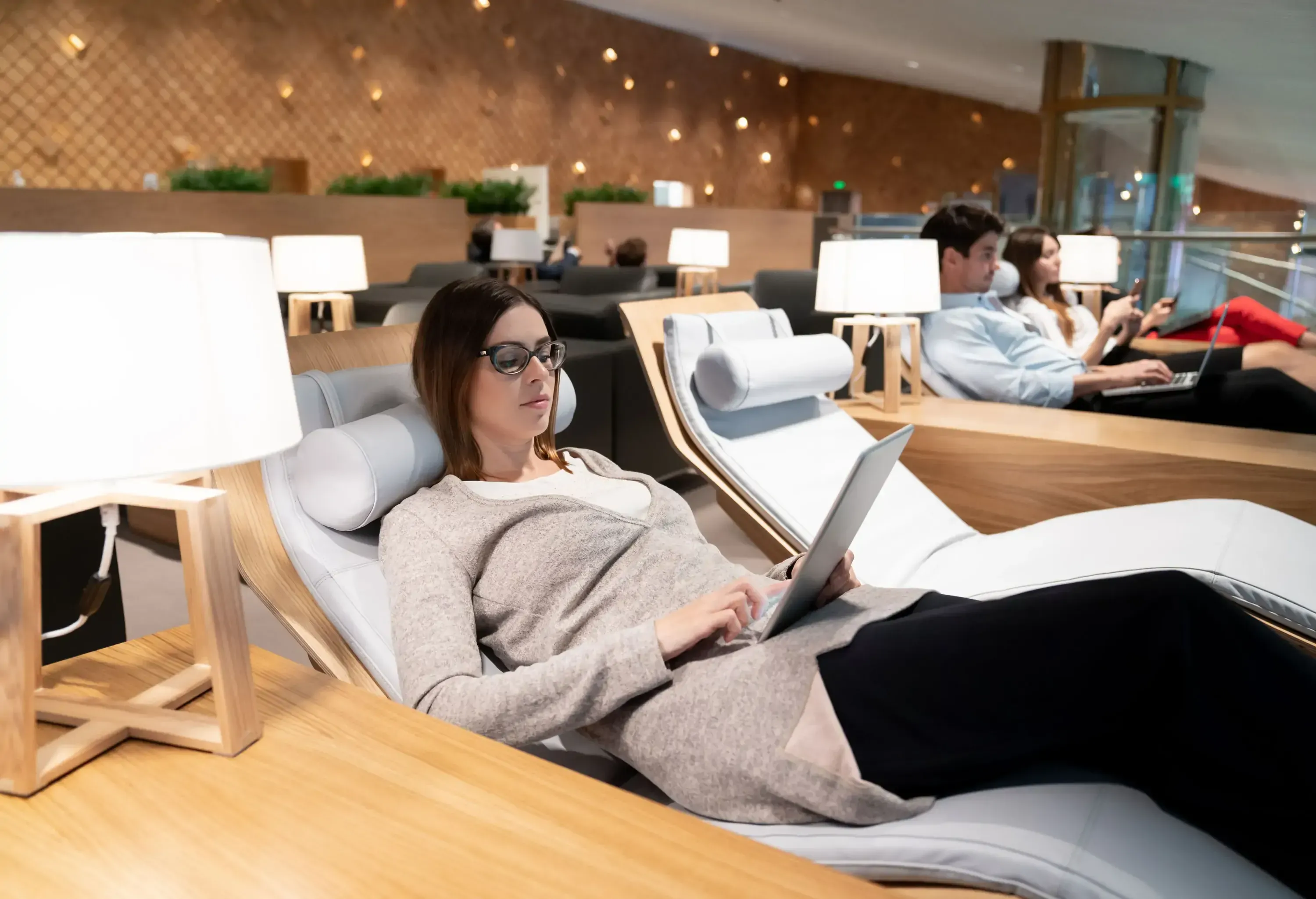 Traveling business woman relaxing in a VIP lounge at the airport using her tablet computer while waiting for her flight - travel concepts