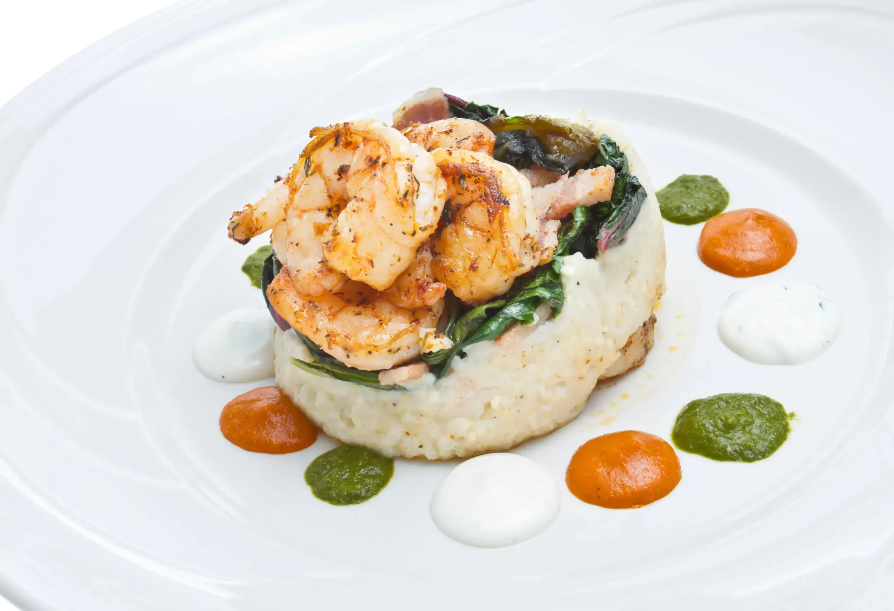 Cajun Jumbo Shrimp and Grits are artfully plated with a luscious savoury sauce, showcasing a delightful combination of spicy and creamy flavours in a visually stunning presentation.