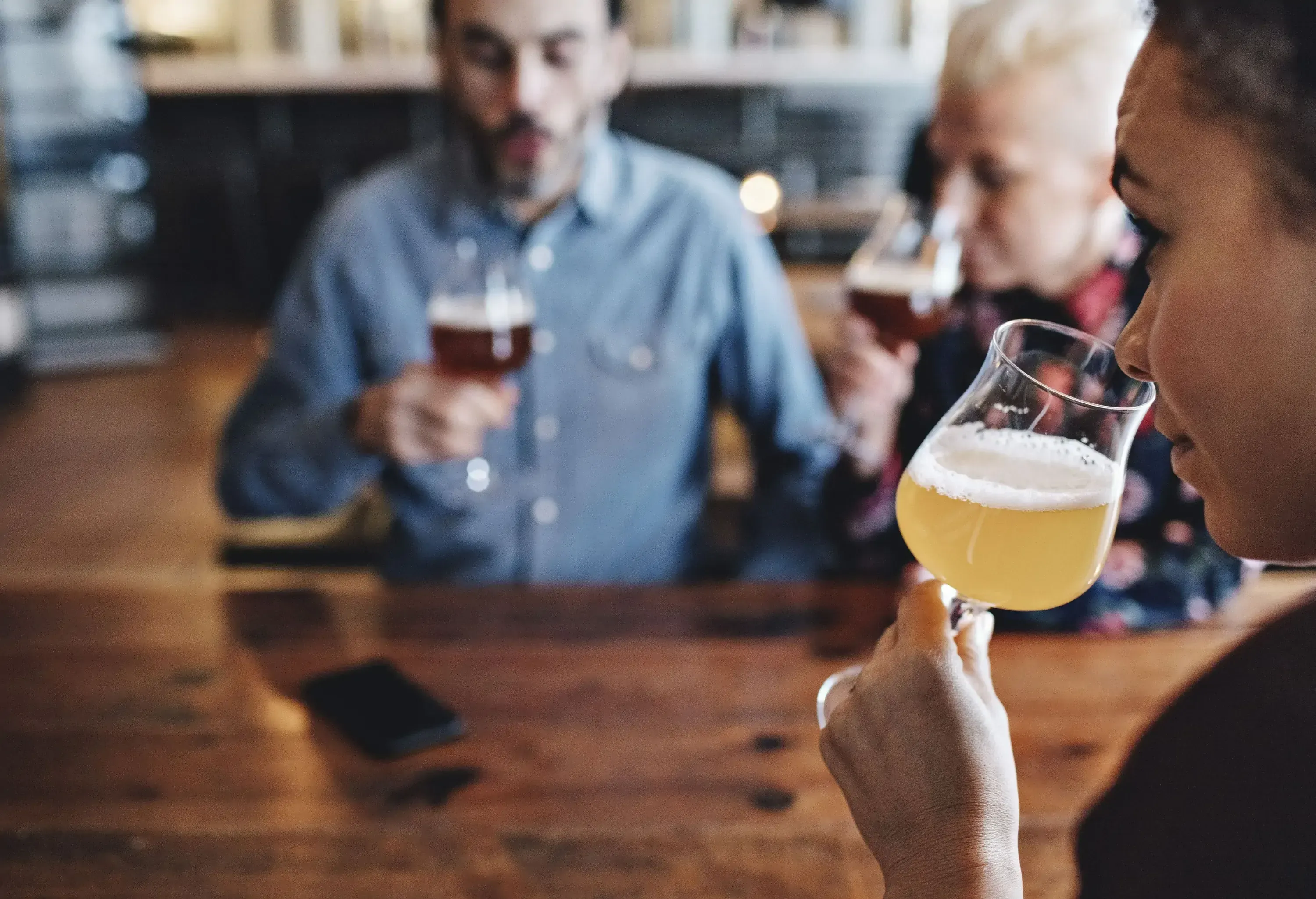 A woman smells a craft beer from a glass.
