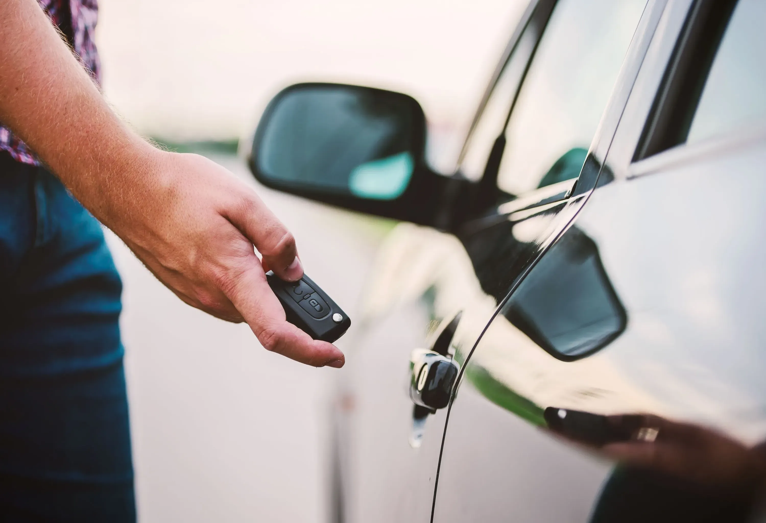 A person unlocking a car using a key fob.