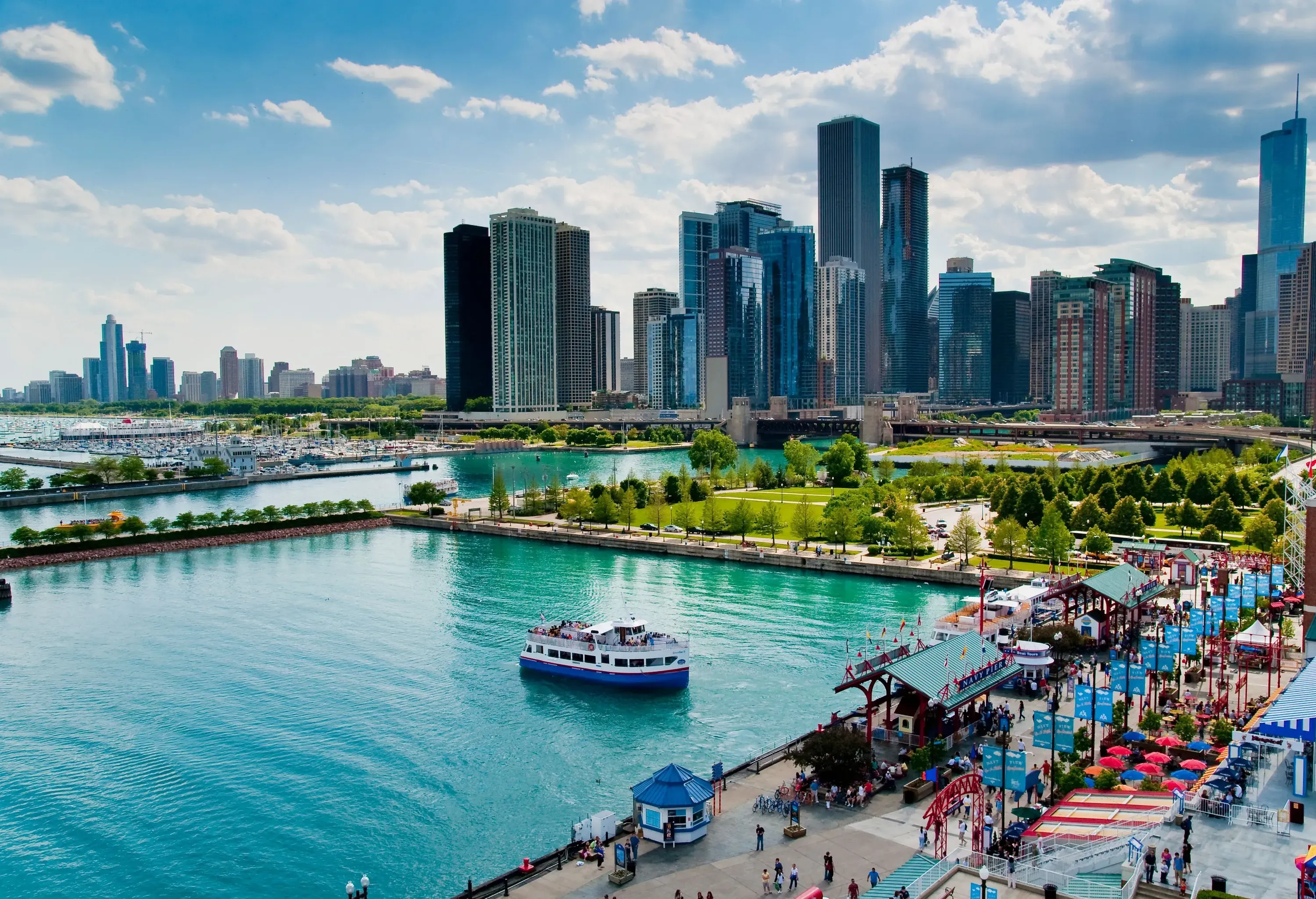A passenger boat on a busy pier with views of the city centre skyline.