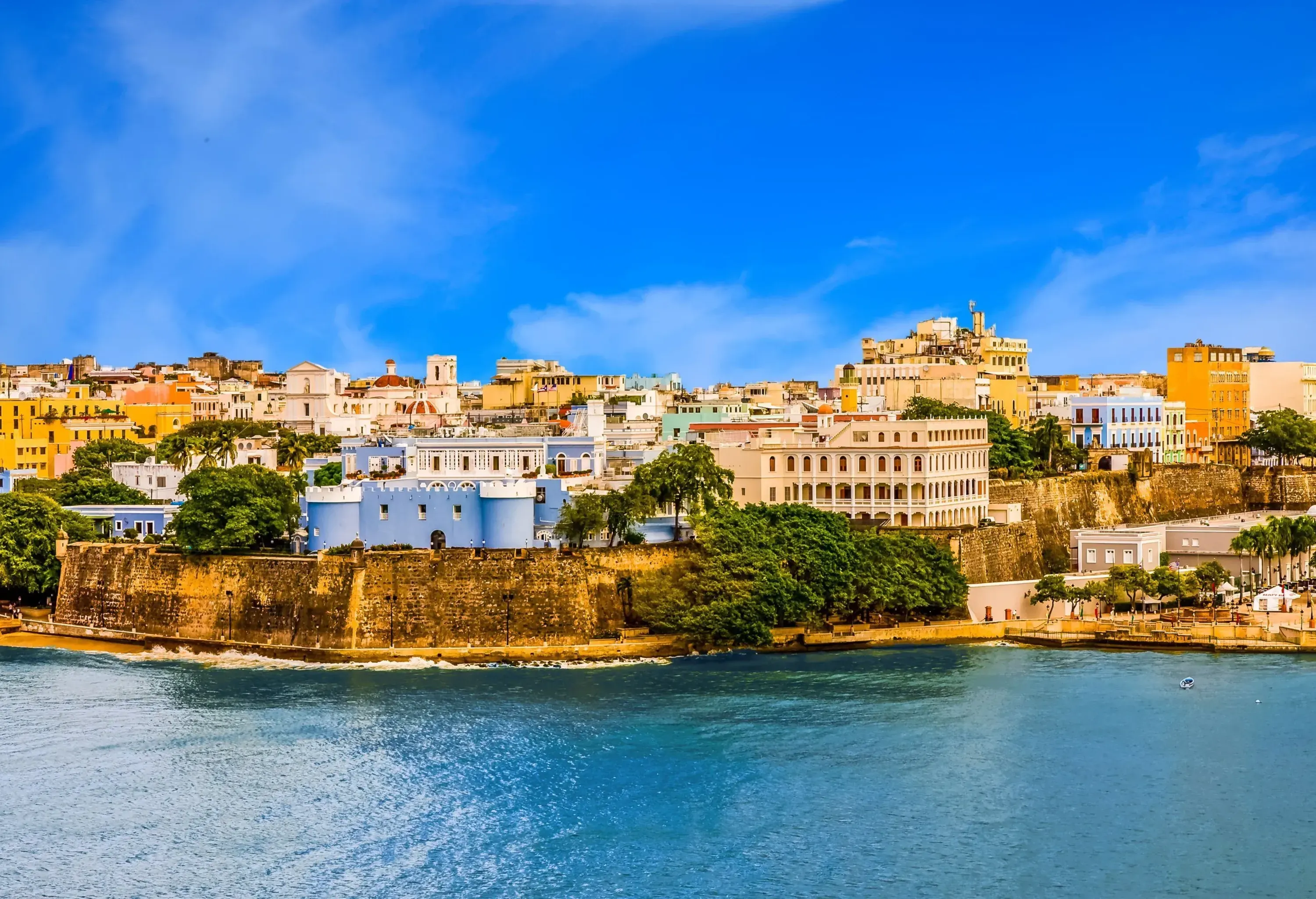 A fortified seaside town with colourful and historic architecture behind the sturdy walls.