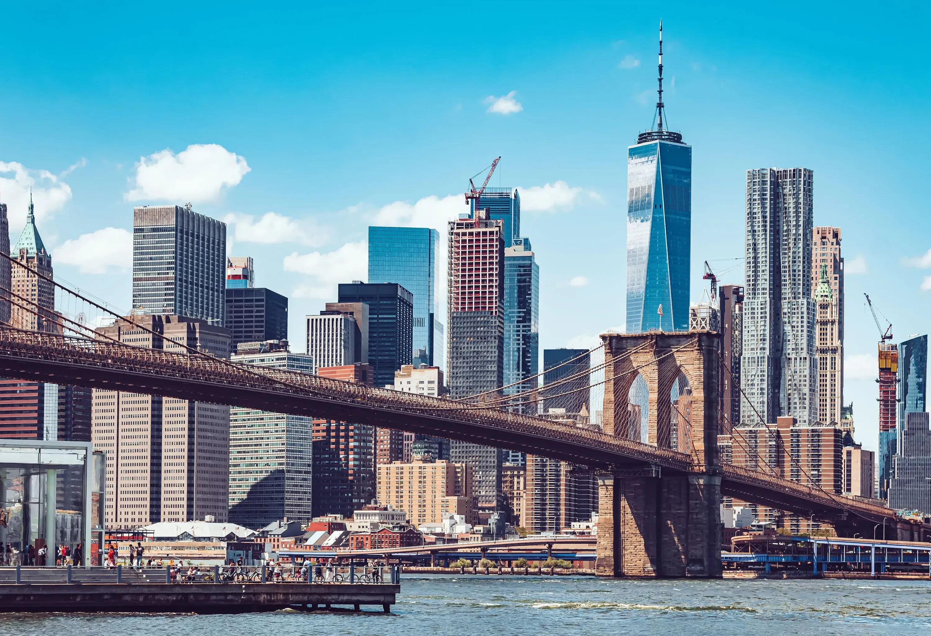 A suspension bridge across a bay against the backdrop of a city skyline.