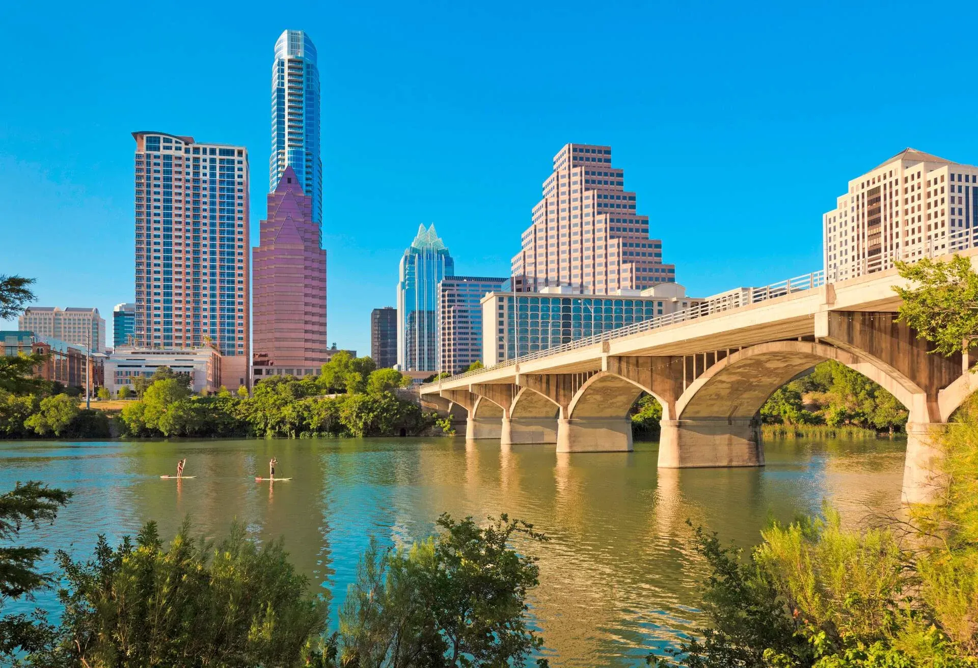 golden hour light illuminates Stand up Paddleboarders on Ladybird Lake and Congress Avenue Bridge, Austin Texas skyline