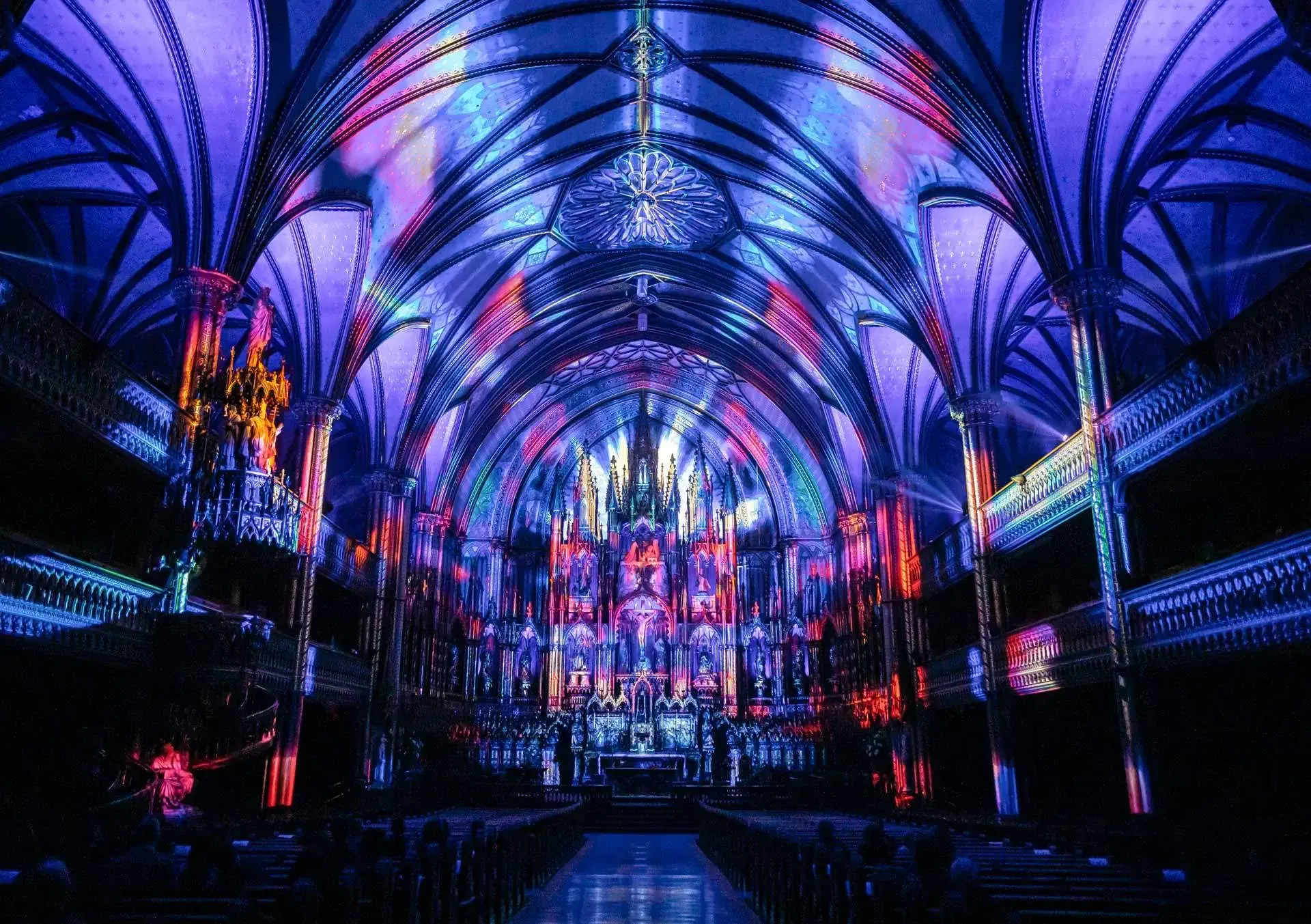 Interior of historic building lit with vivid blue and purple projections.