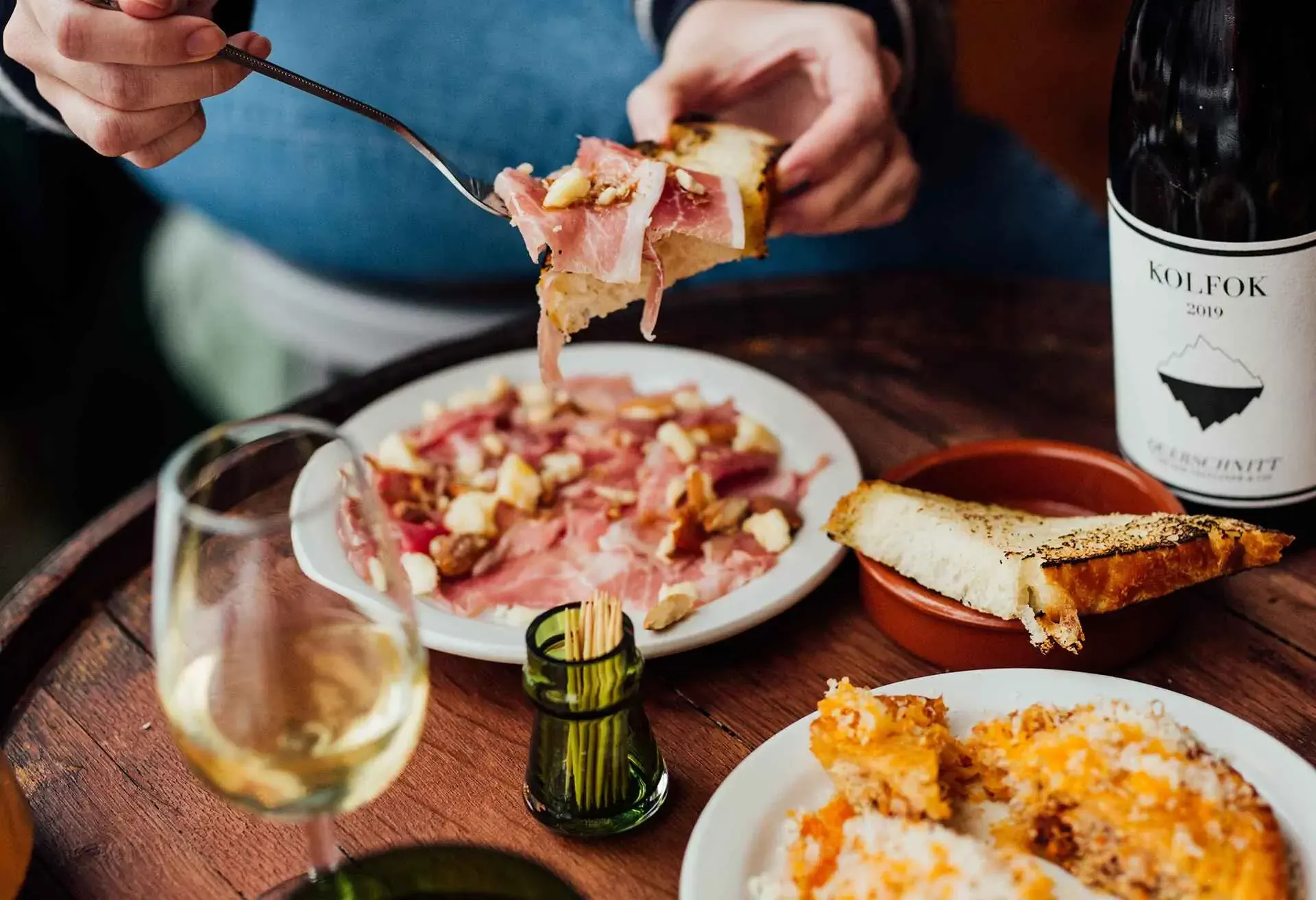 People eating prosciutto and drinking wine