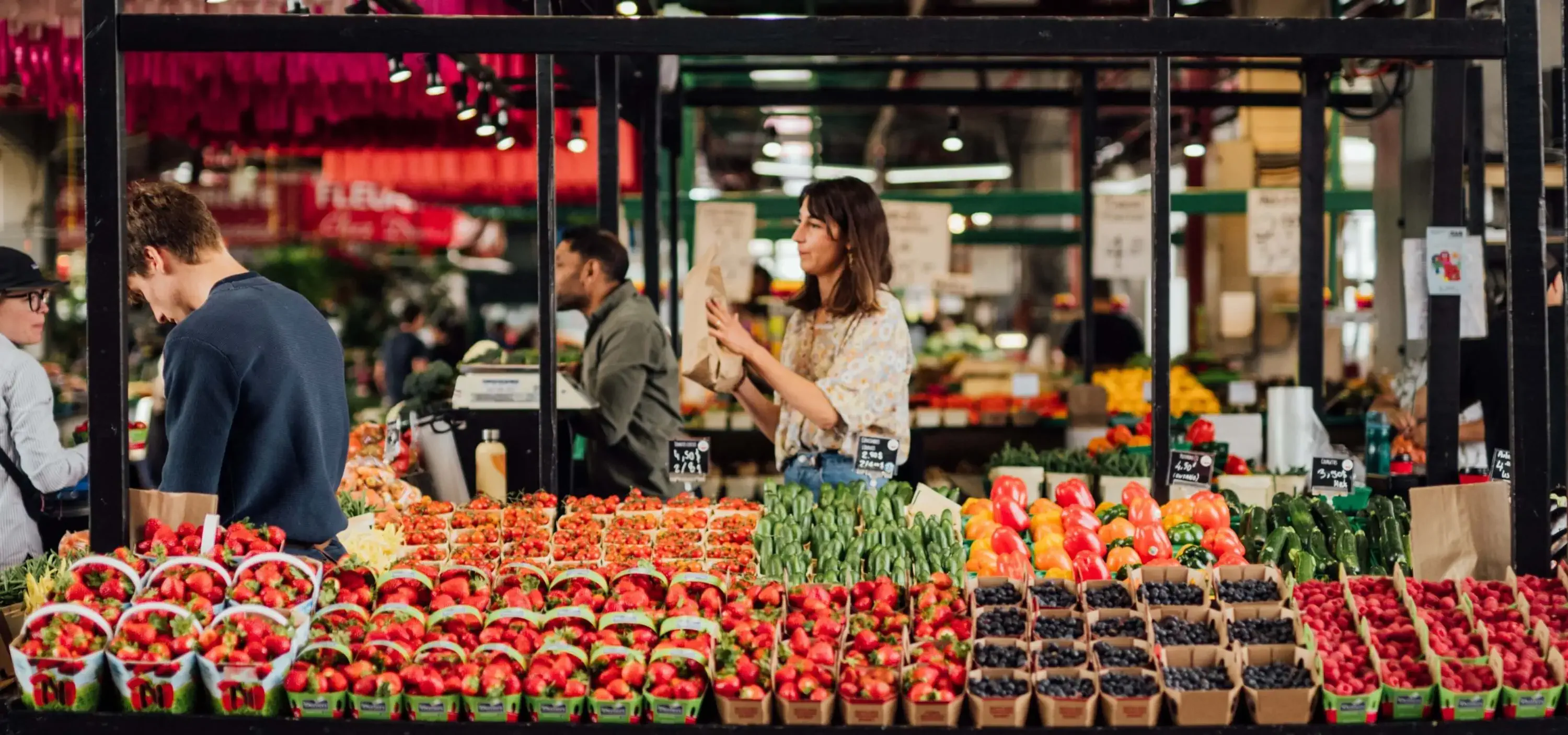 Woman shopping at a farmer’s market with fresh produce in baskets