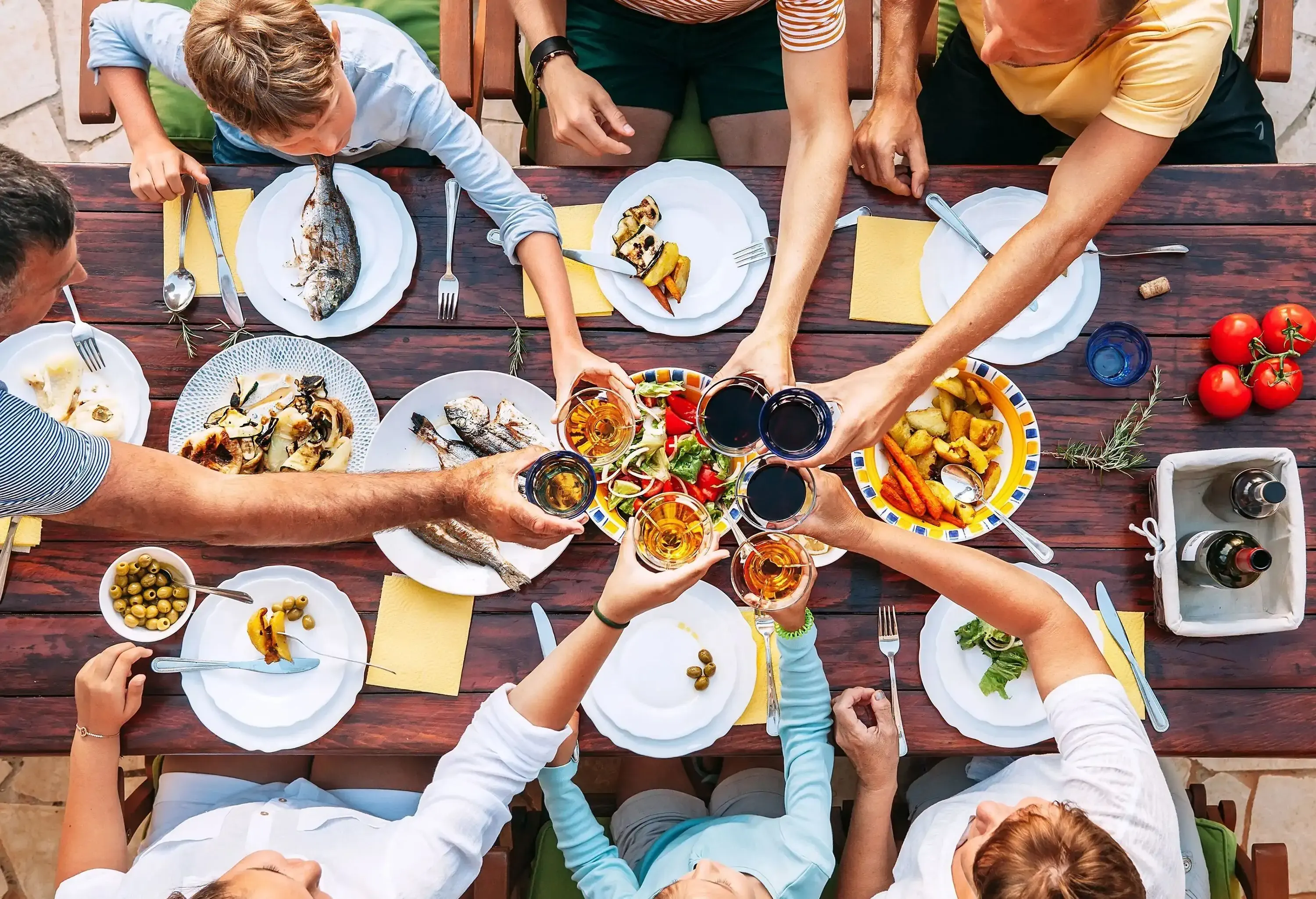 A group of friends making a toast over a wooden table laden with food.