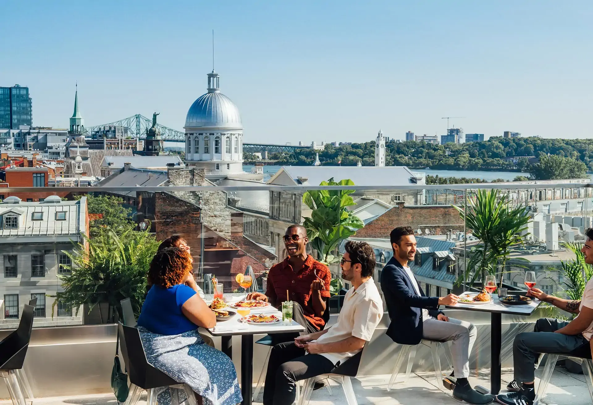 Friends enjoying food and drinks on a rooftop with a cityscape view