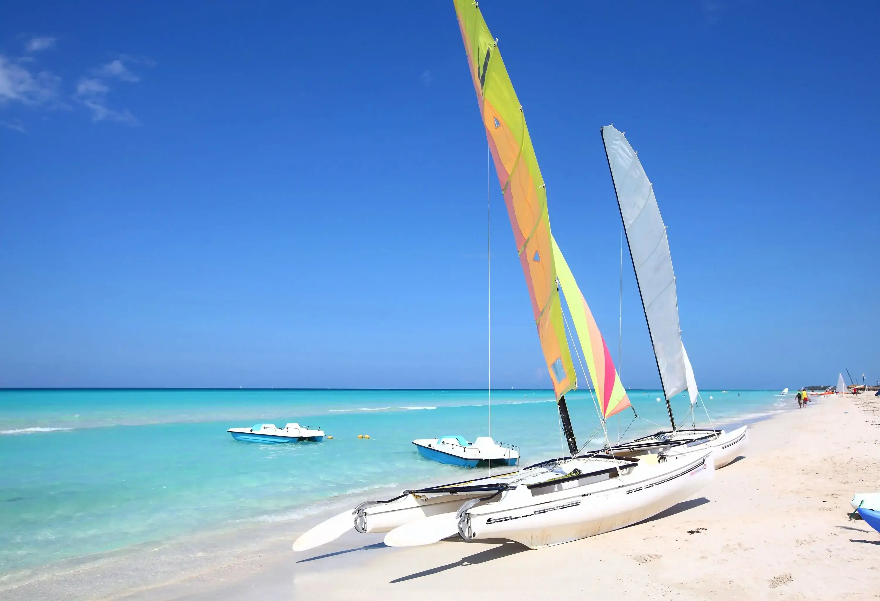 Catamarans and speed boats on the white sandy shore of the turquoise beach.