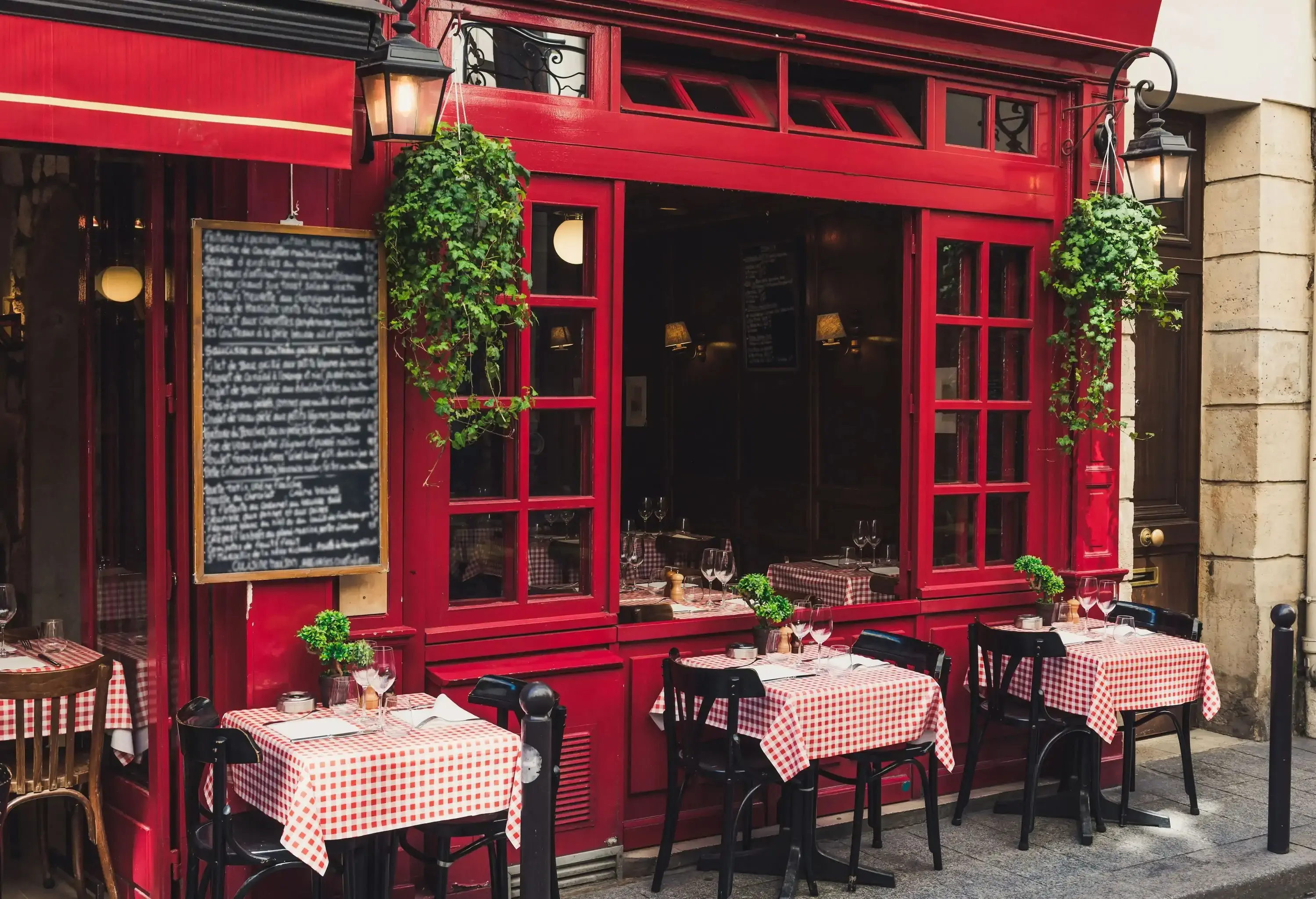 A charming red café with tables and chairs on the sidewalk.