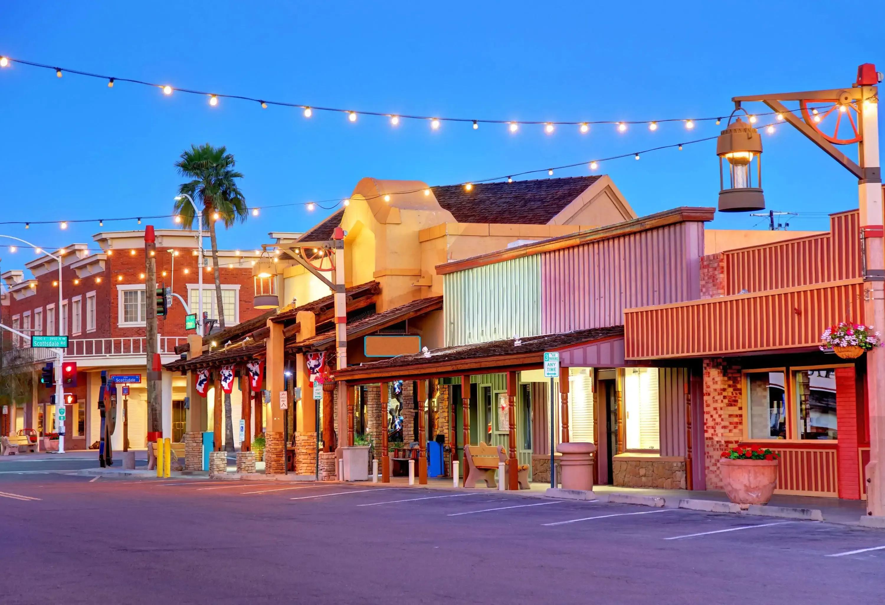A bustling street comes alive with a charming array of shops, their facades adorned with colourful string lights that hang overhead.