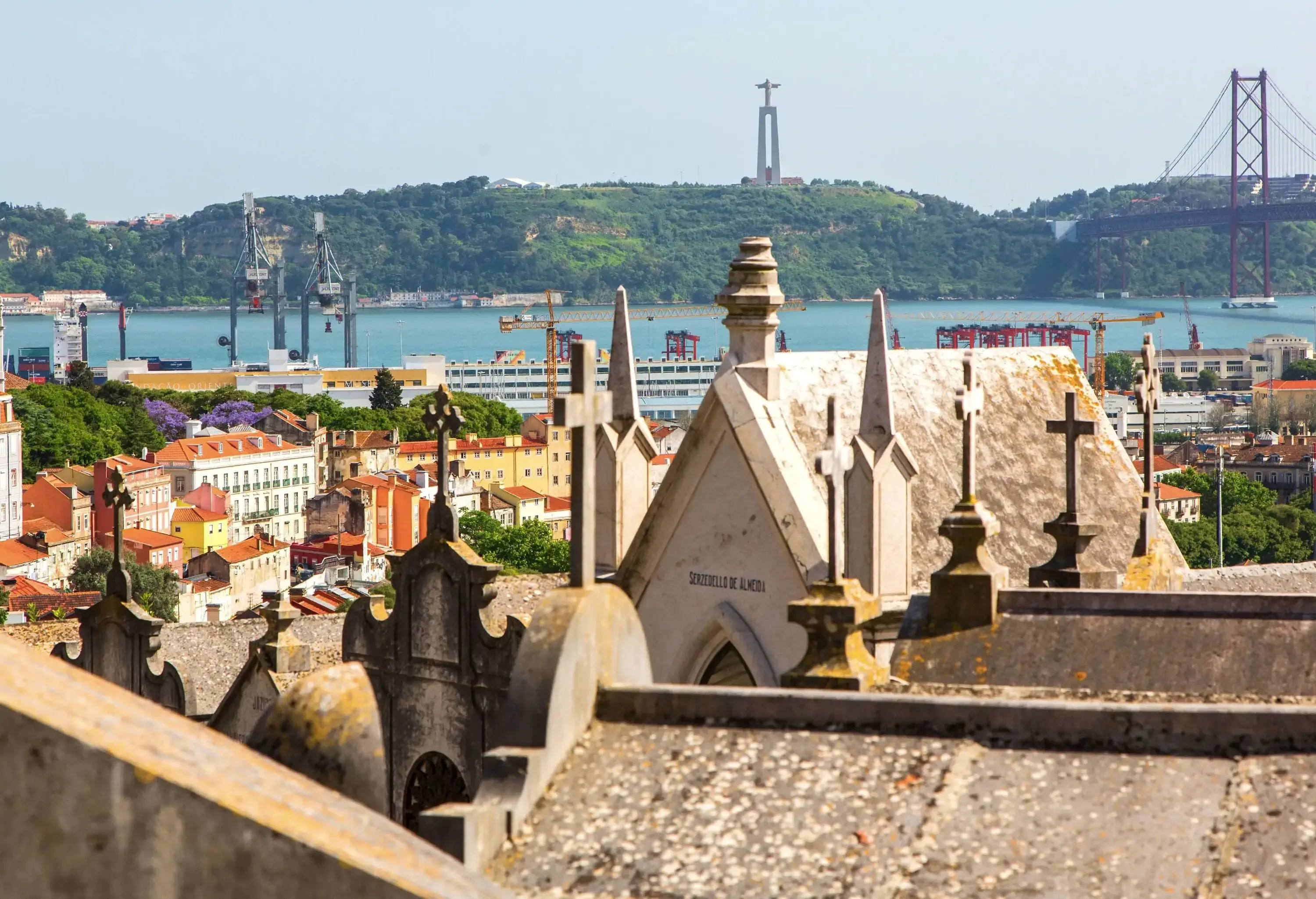 A skyline formed by historic churches and structures by the river crossed by a bridge.