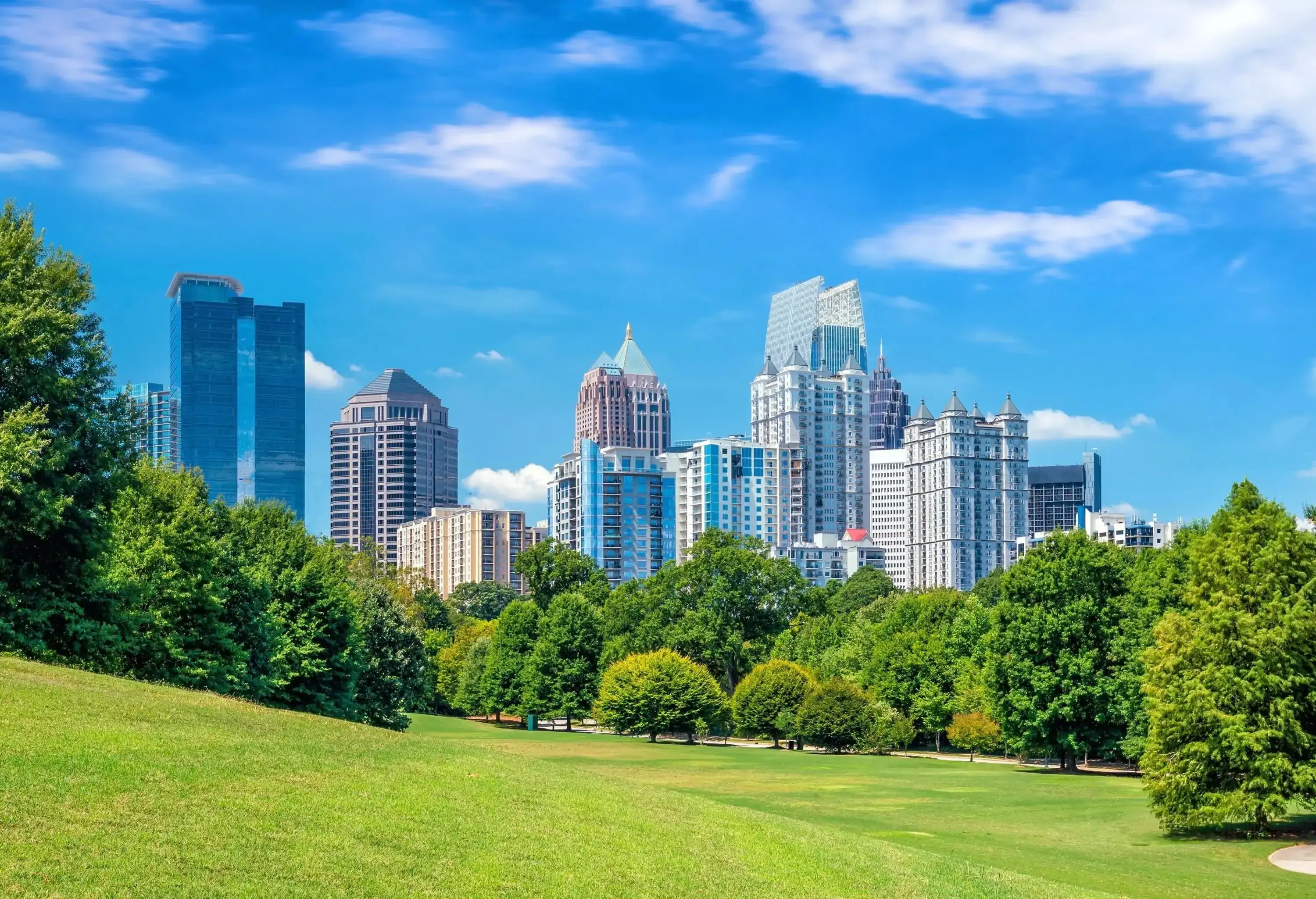 The skyline of midtown rises above the park's lush trees on neatly mowed grass.