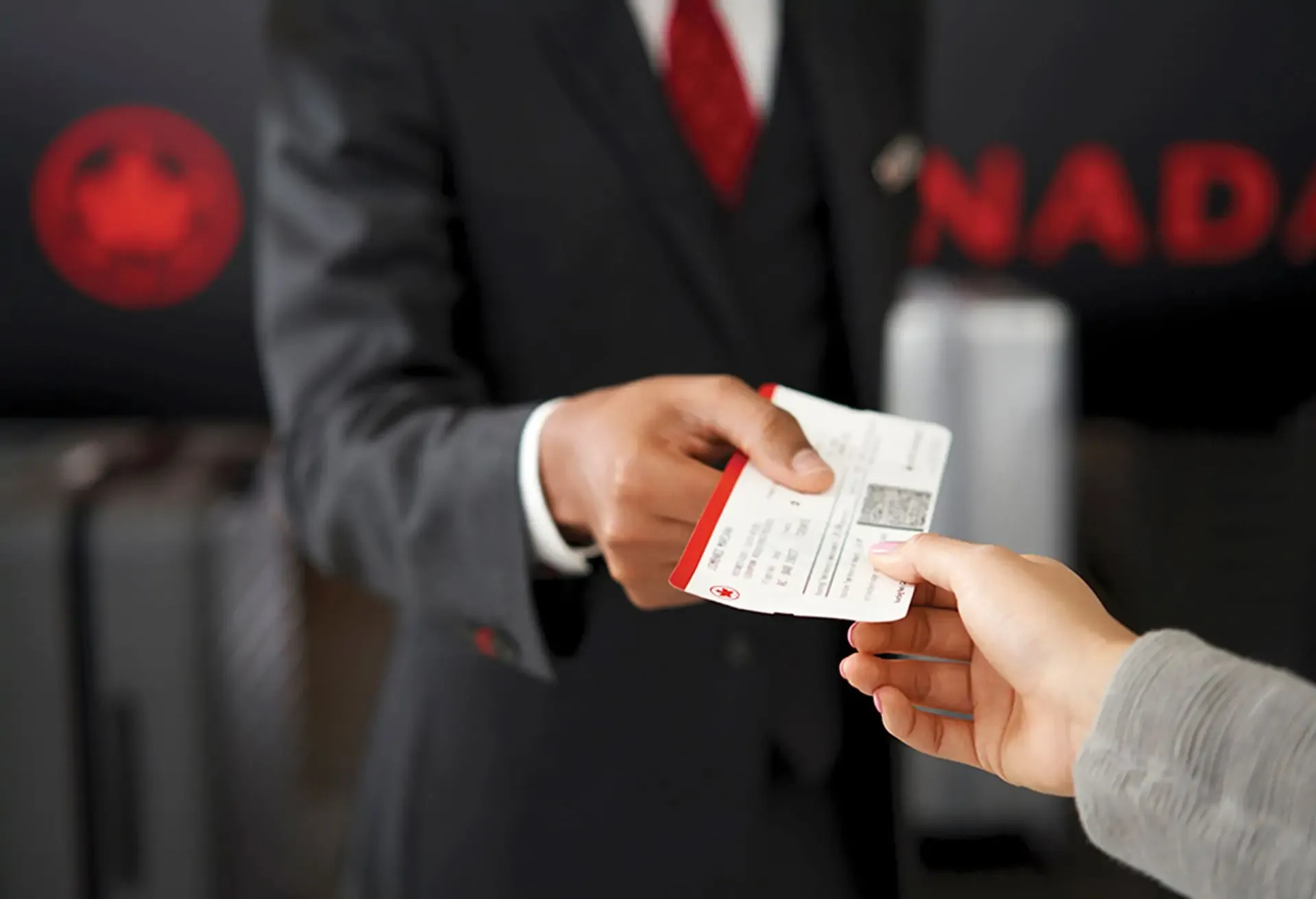 An airline agent handing a boarding pass to a passenger at a check-in counter.