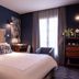 Mom'Art Hotel Paris guest room with king bed, dark blue walls, desk, armchair and tall window