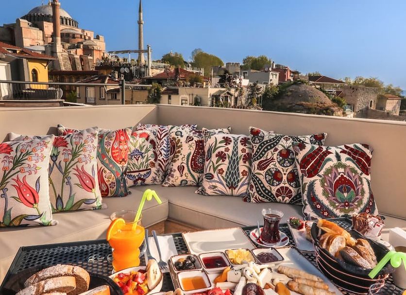Henna Hotel Istanbul rooftop terrace with breakfast, cushions, and Istanbul city views
