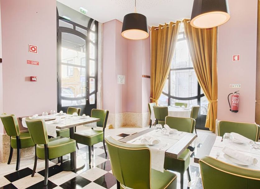 Hotel Lis Baixa Lisbon dining room with green chairs, set tables, and tall windows with gold curtains