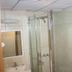 Duen Hotel in Delmas bathroom with glass-enclosed shower, sink, mirror, and wall-mounted TV