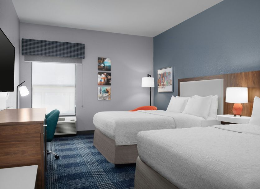 Hampton Inn Russellville guest room with two beds, desk, window and blue carpet