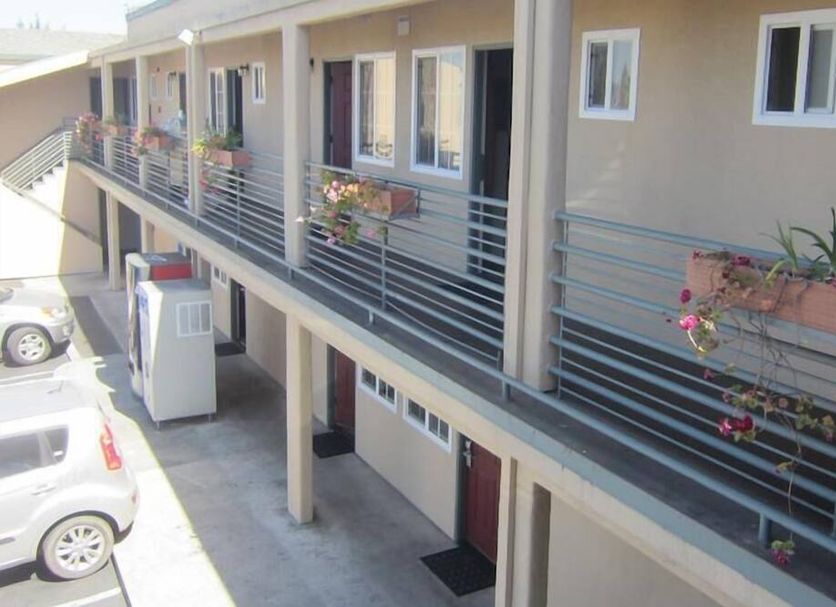 Pacific Best Inn in Seaside exterior walkway with railings, parked cars, and second-floor guest rooms