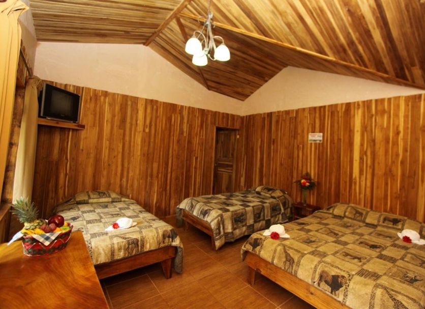 Historias Lodge in Monteverde guest room with three beds and wood-paneled walls