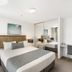 Rhapsody Resort Surfers Paradise guest room with king bed, bedside lamps, mirrored wardrobe and desk