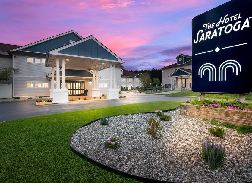 The Hotel Saratoga in Saratoga Springs exterior with landscaped entrance and sunset sky