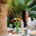 Napper By Rottenberg in Havana, woman reading a newspaper at an outdoor café table amid lush greenery