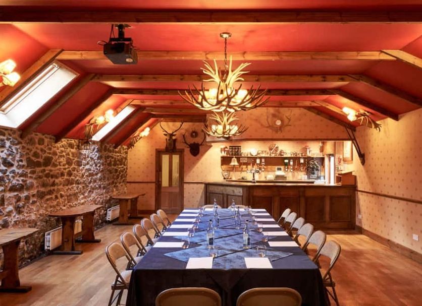 Loch Kinord Hotel in Aboyne, banquet room with long set dining table and stone accent wall