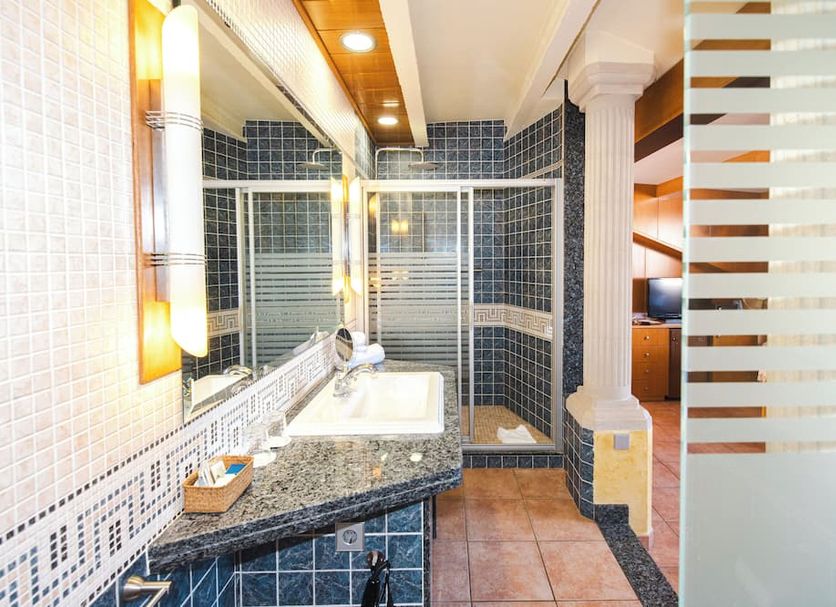 Hotel Plaça in Sant Feliu de Guíxols bathroom with tiled shower, vanity sink and stone countertop