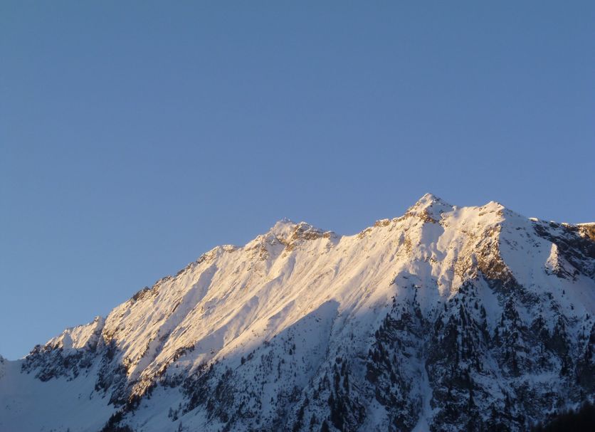 Santa San in Ayas with snow-covered mountain peaks under a clear blue sky