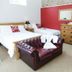 Newsham Grange Farm, Thirsk: guest room with two beds, red accent wall, dresser and leather bench